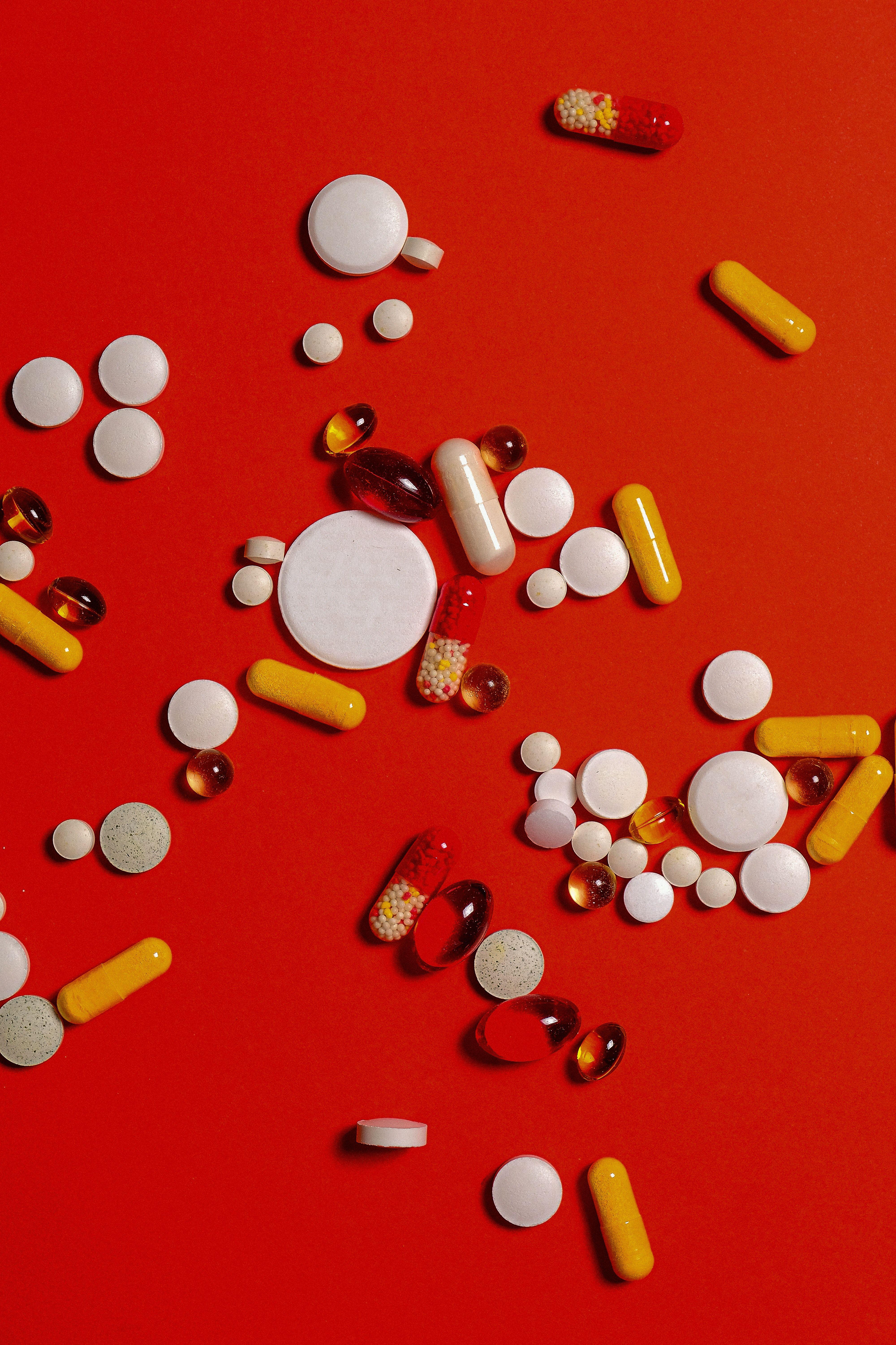 4000x6000 Different Medication Pills And Capsules on Red Background · Free