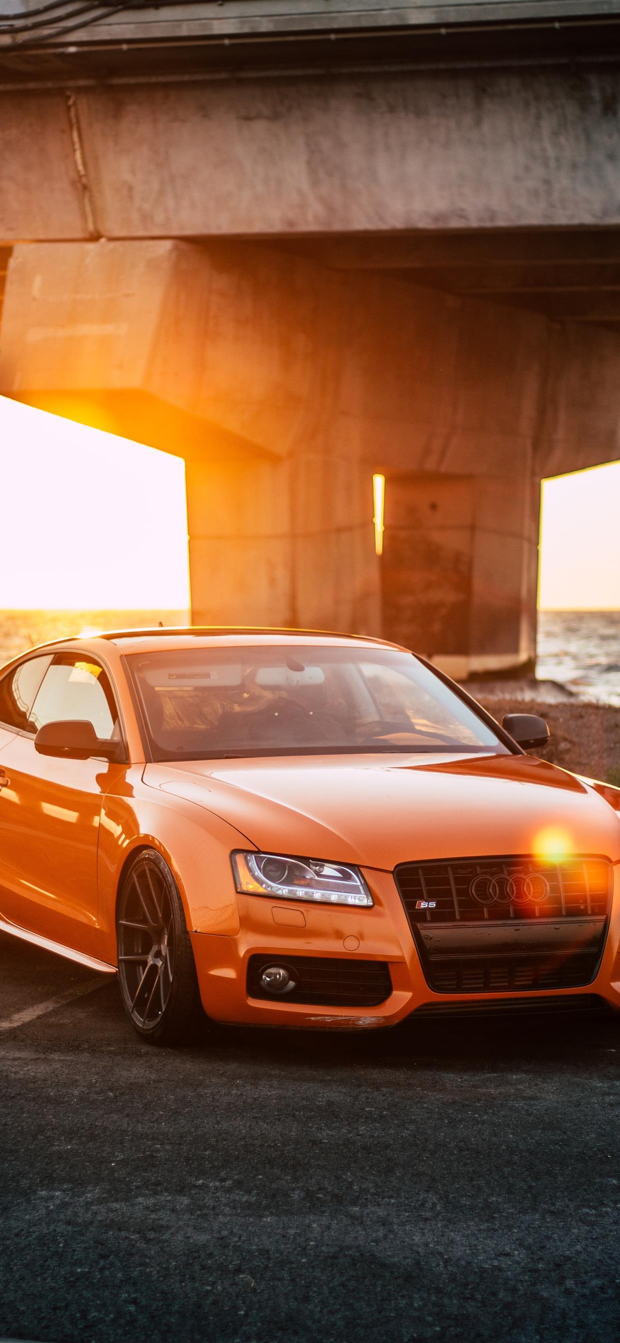 1242x2688 orange Audi coupe parked on gray concrete road iPhone X Wallpaper