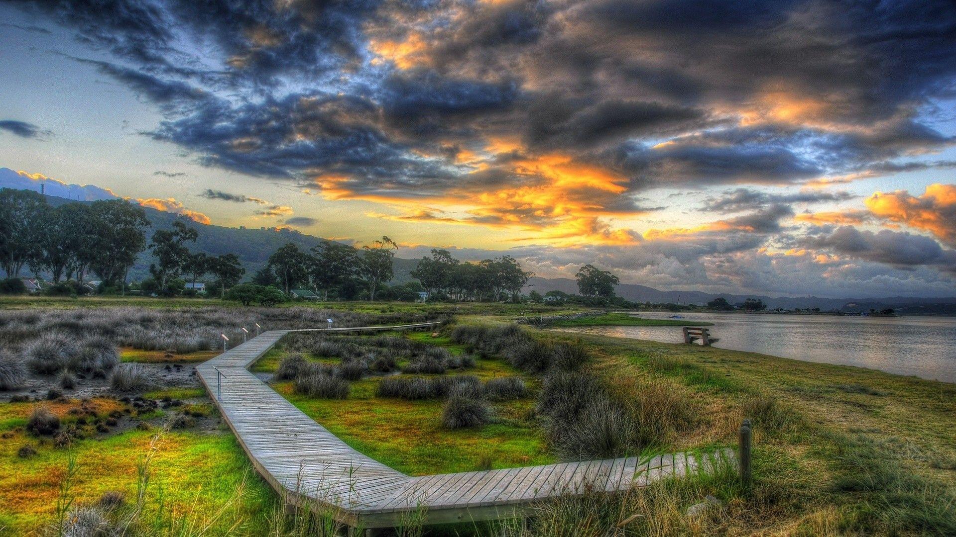 1920x1080 Grass: Boardwalk Grassy Lakeshore Grass Lake Clouds Bench Wallpaper