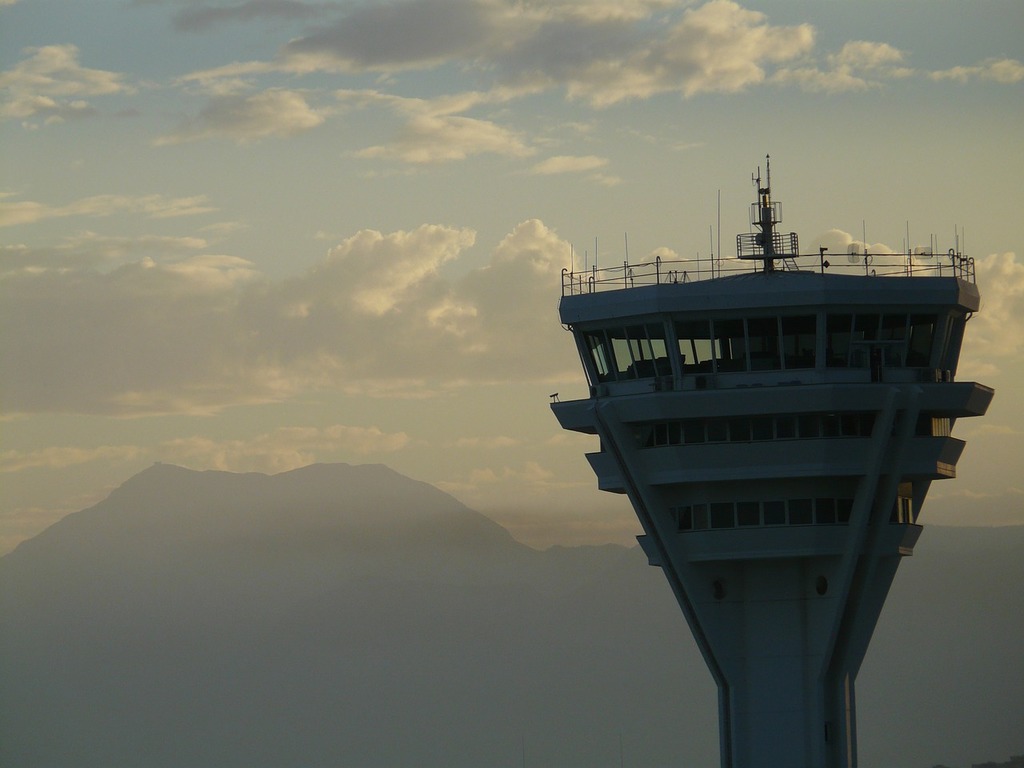1024x768 A large air traffic control tower with mountains in the
