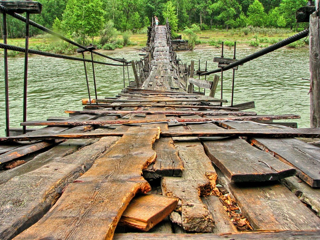 1024x768 A wooden suspension bridge over a river with trees in the
