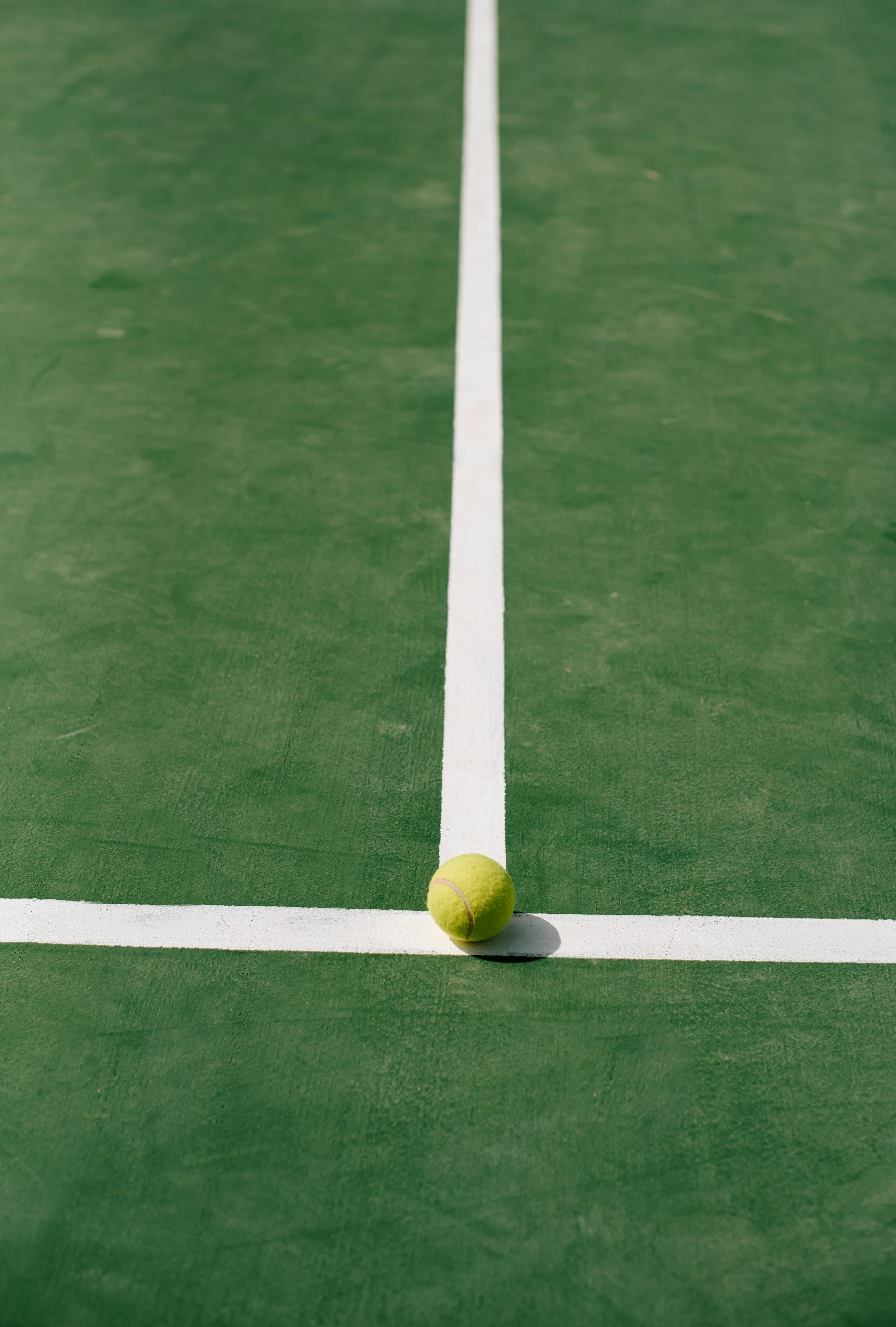 3000x4444 A tennis ball sitting on the edge of a tennis court photo