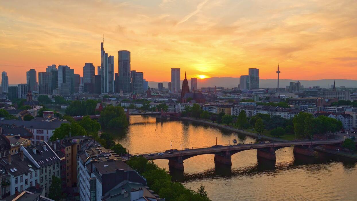 1244x700 Frankfurt Downtown Skyline, Residential Buildings, Bridges, Tram and Main River at Fiery Sunset. Aerial View. Golden Hour. Hesse, Germany