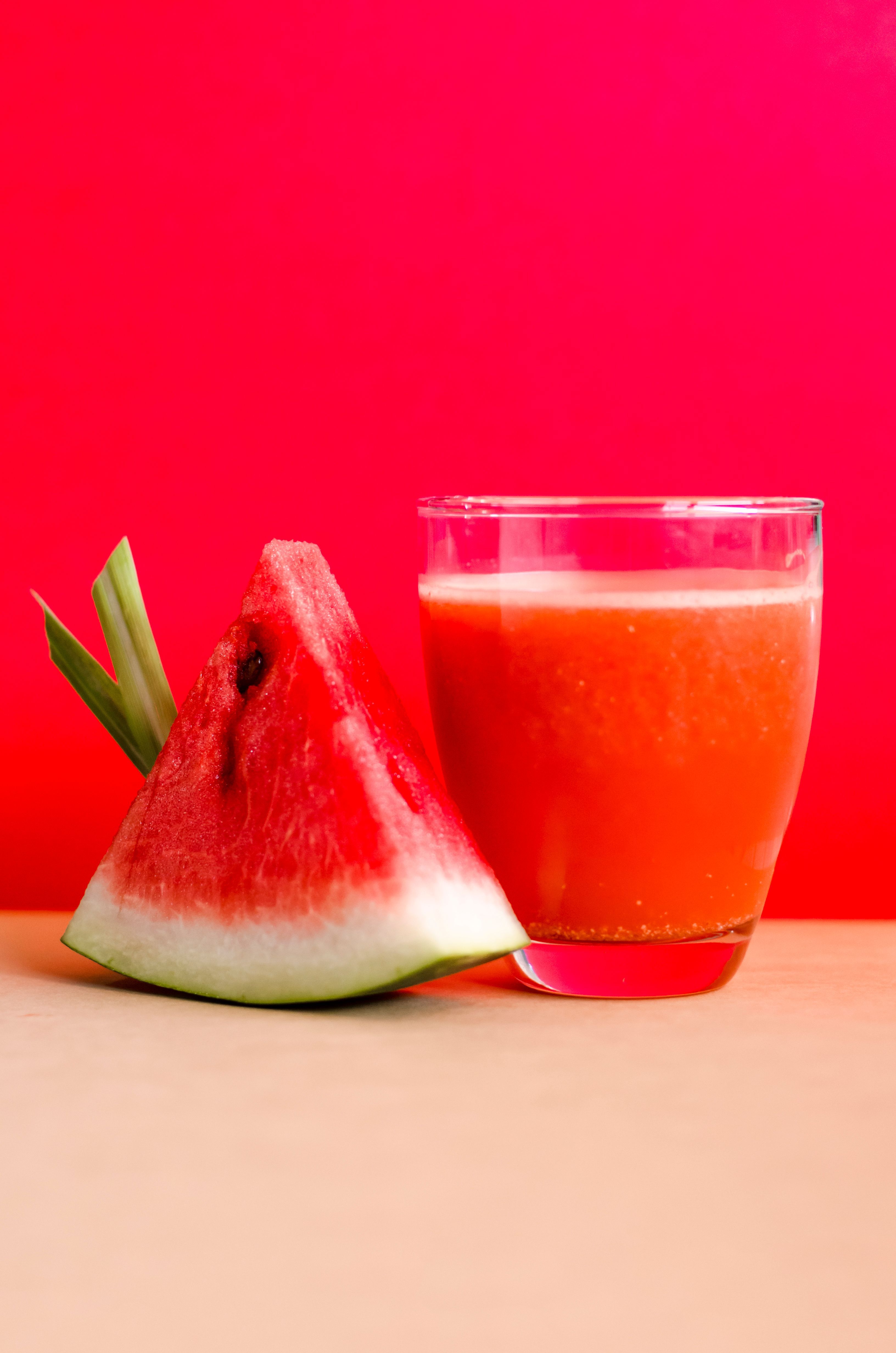 3264x4928 Watermelon Shake Filled Glass Cup Beside Sliced Watermelon Fruit on Brown Surface · Free