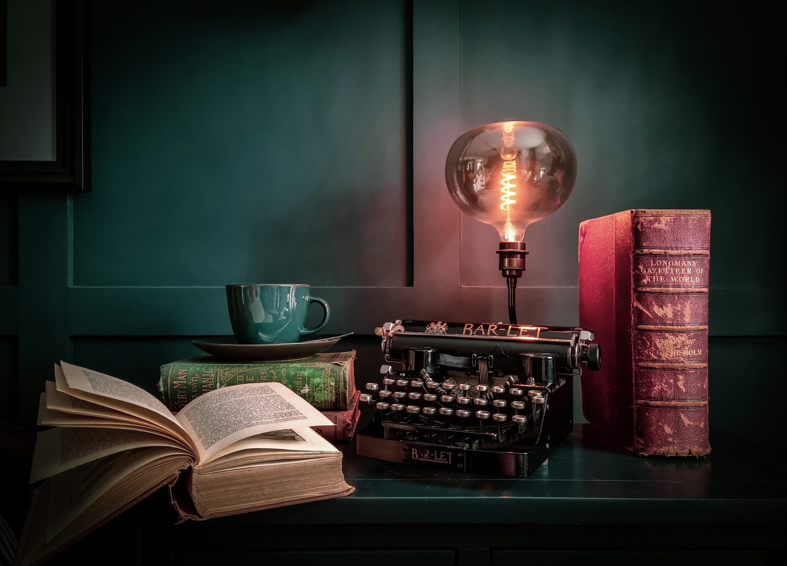 3000x2157 A table with a lamp, a book, and a typewriter on it photo
