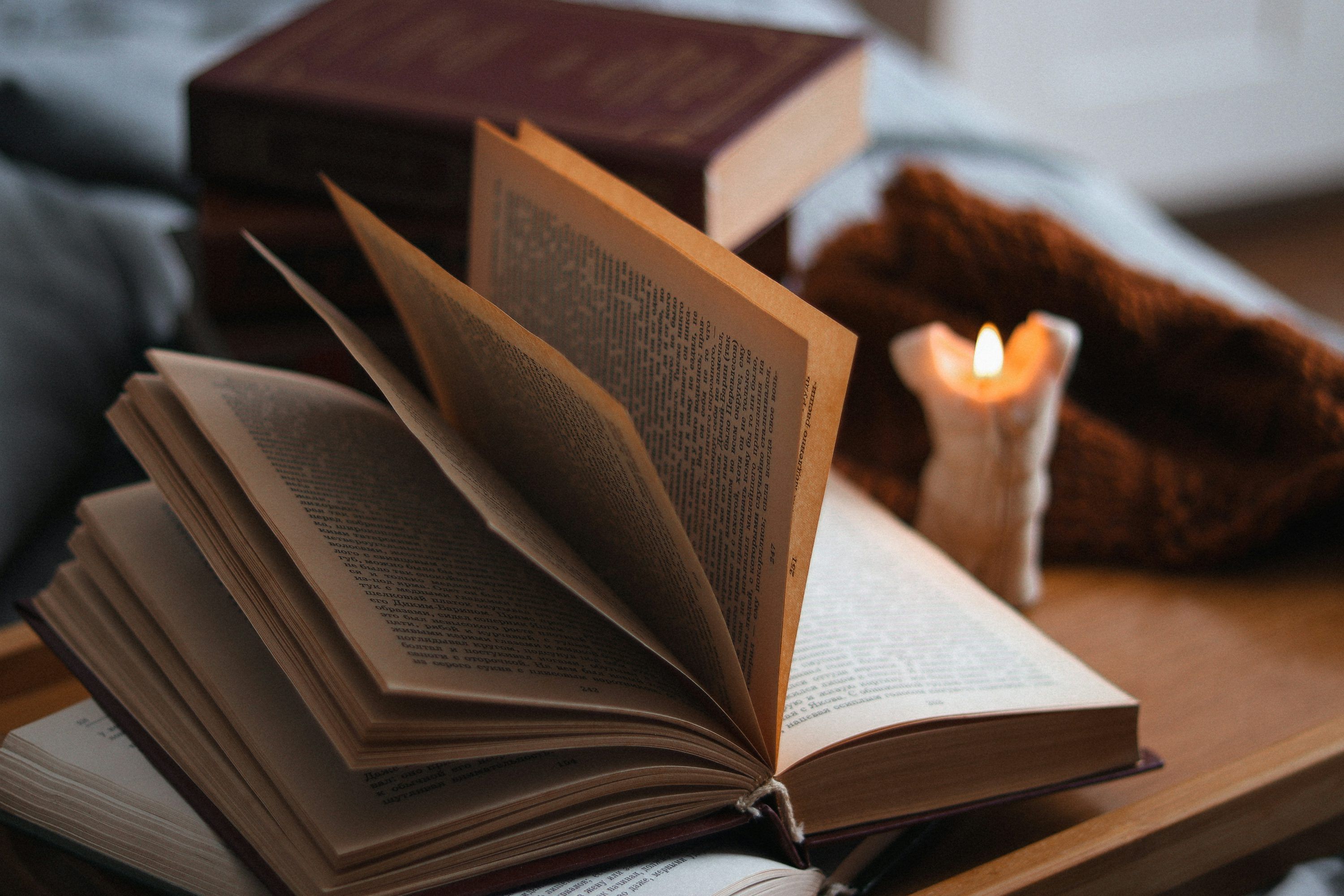 3000x2000 An open book sitting on top of a table next to a candle photo