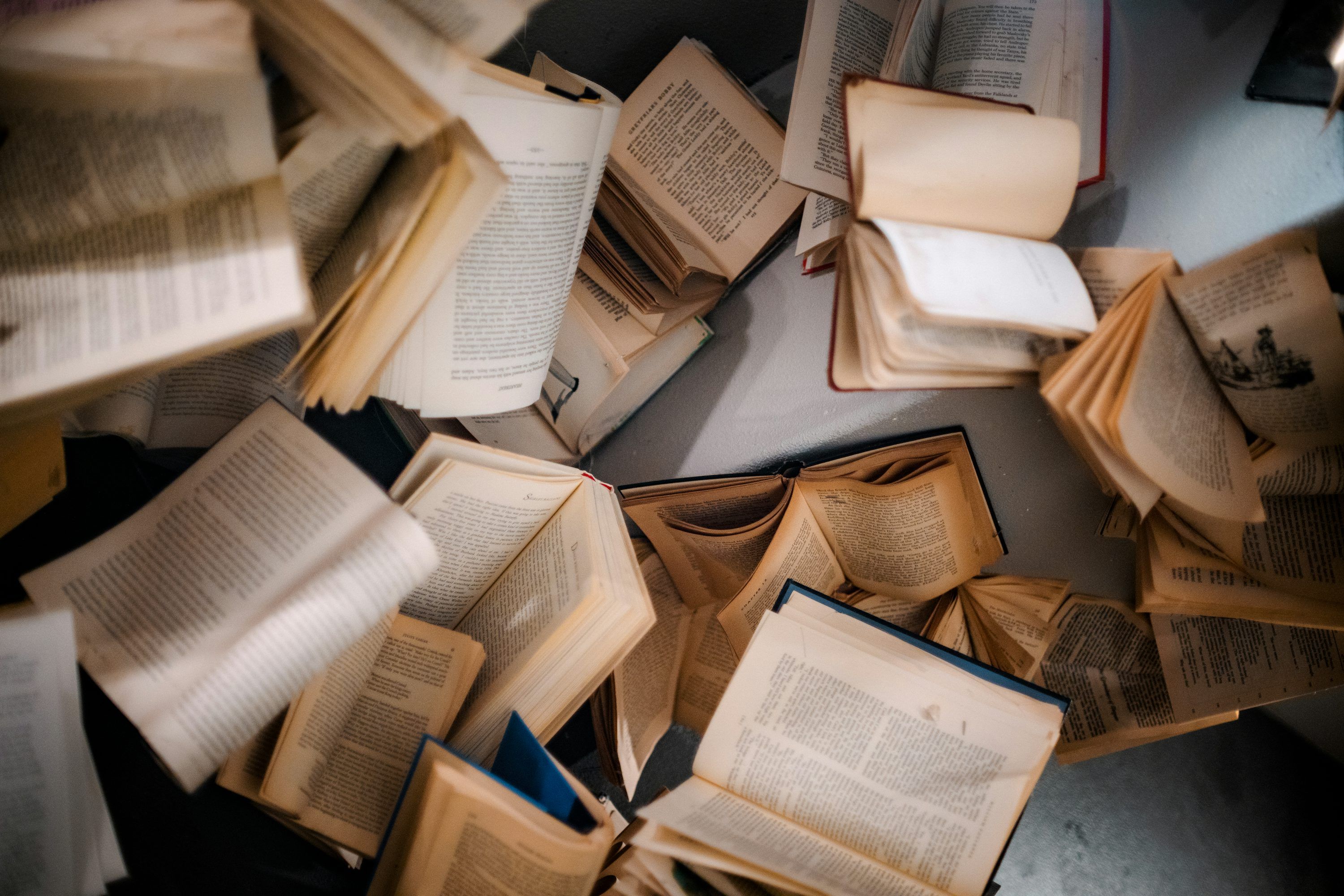 3000x2001 A pile of open books sitting on top of a table photo