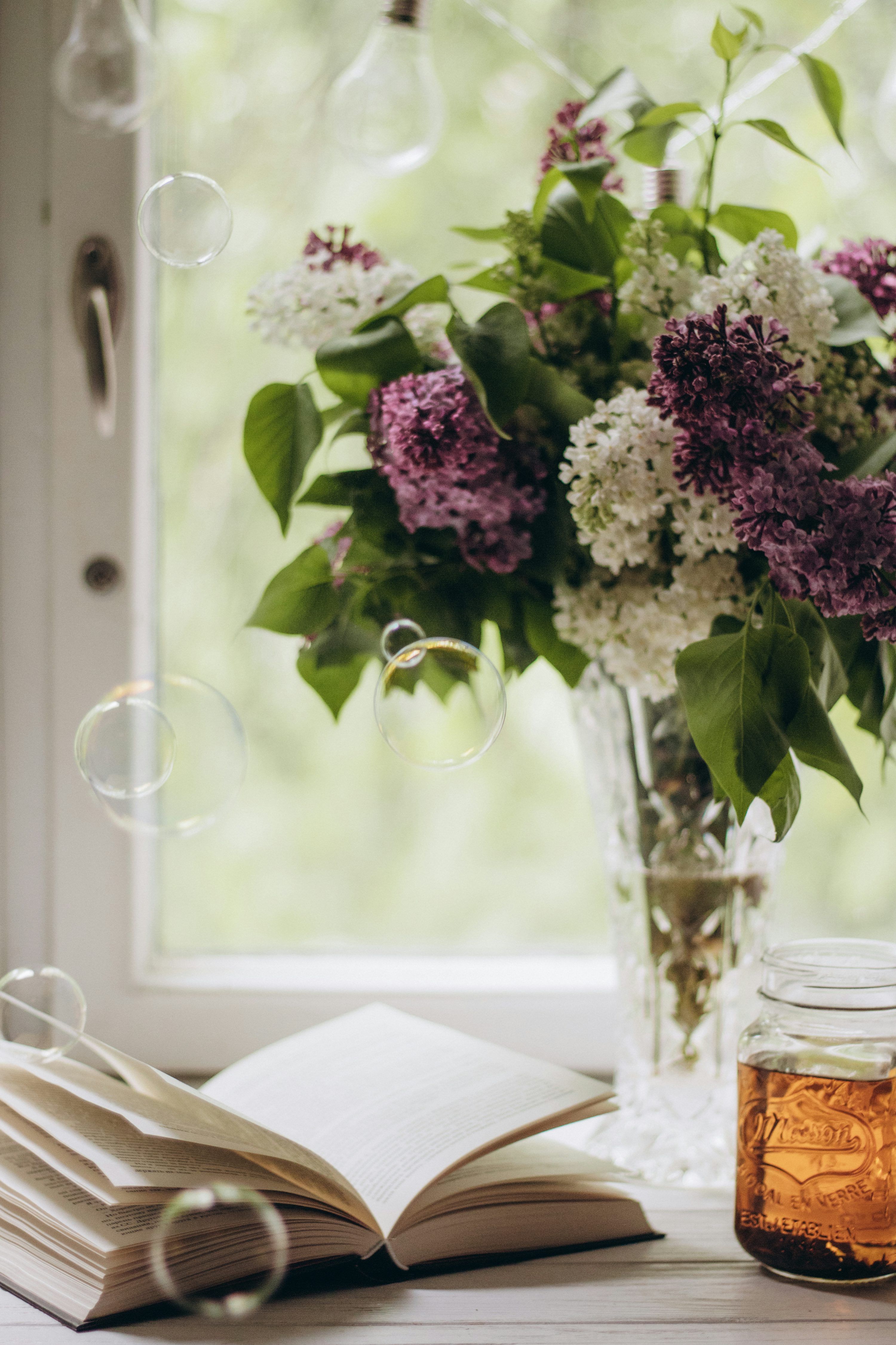 3000x4500 A vase of flowers and a book on a table photo