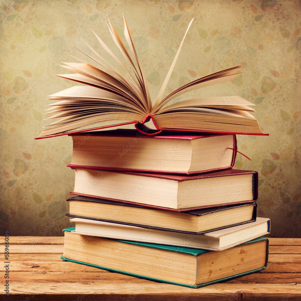 1000x1000 Vintage old books on wooden table over retro wallpaper