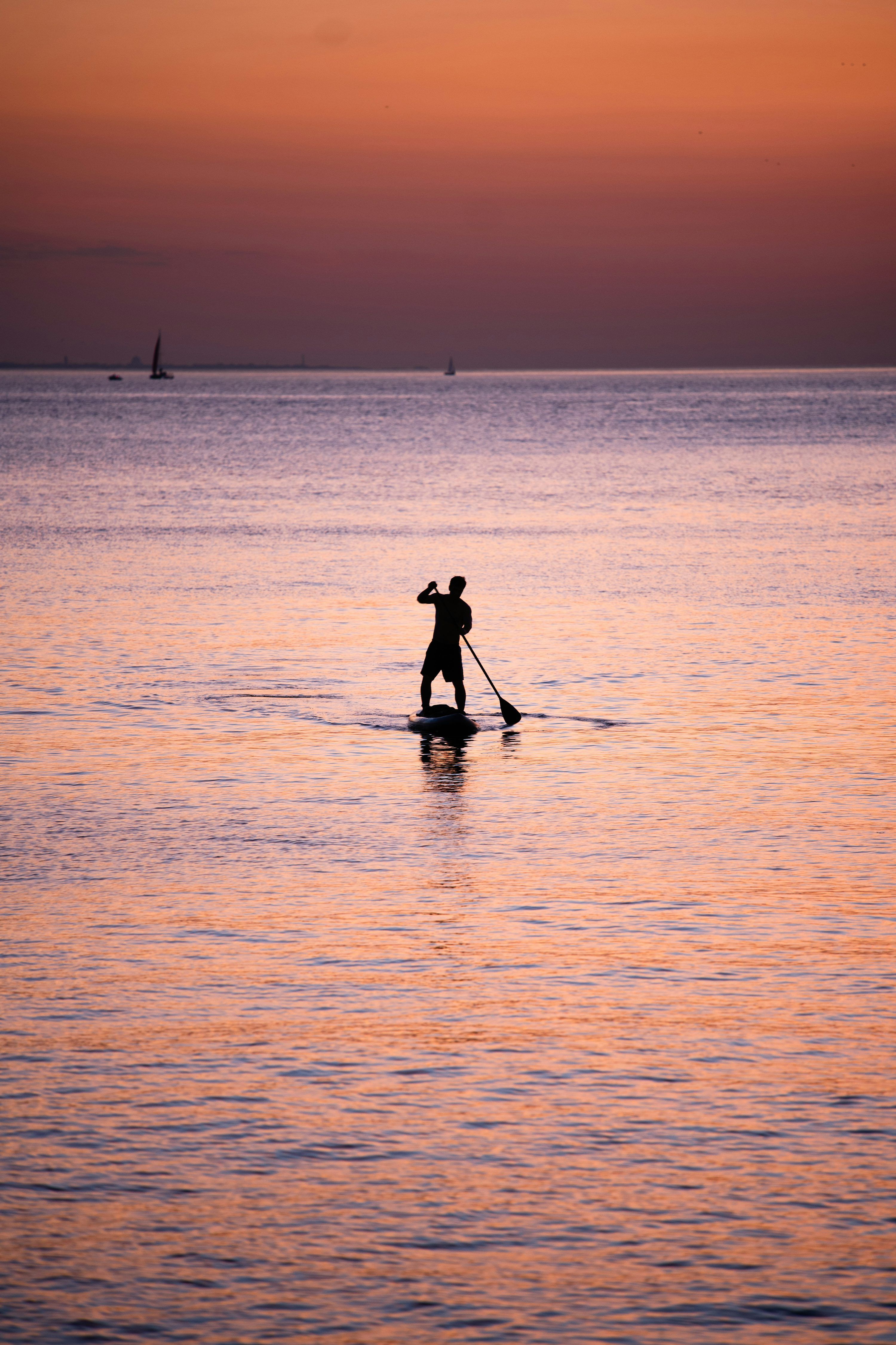 3000x4500 A man riding a paddle board on top of a body of water photo