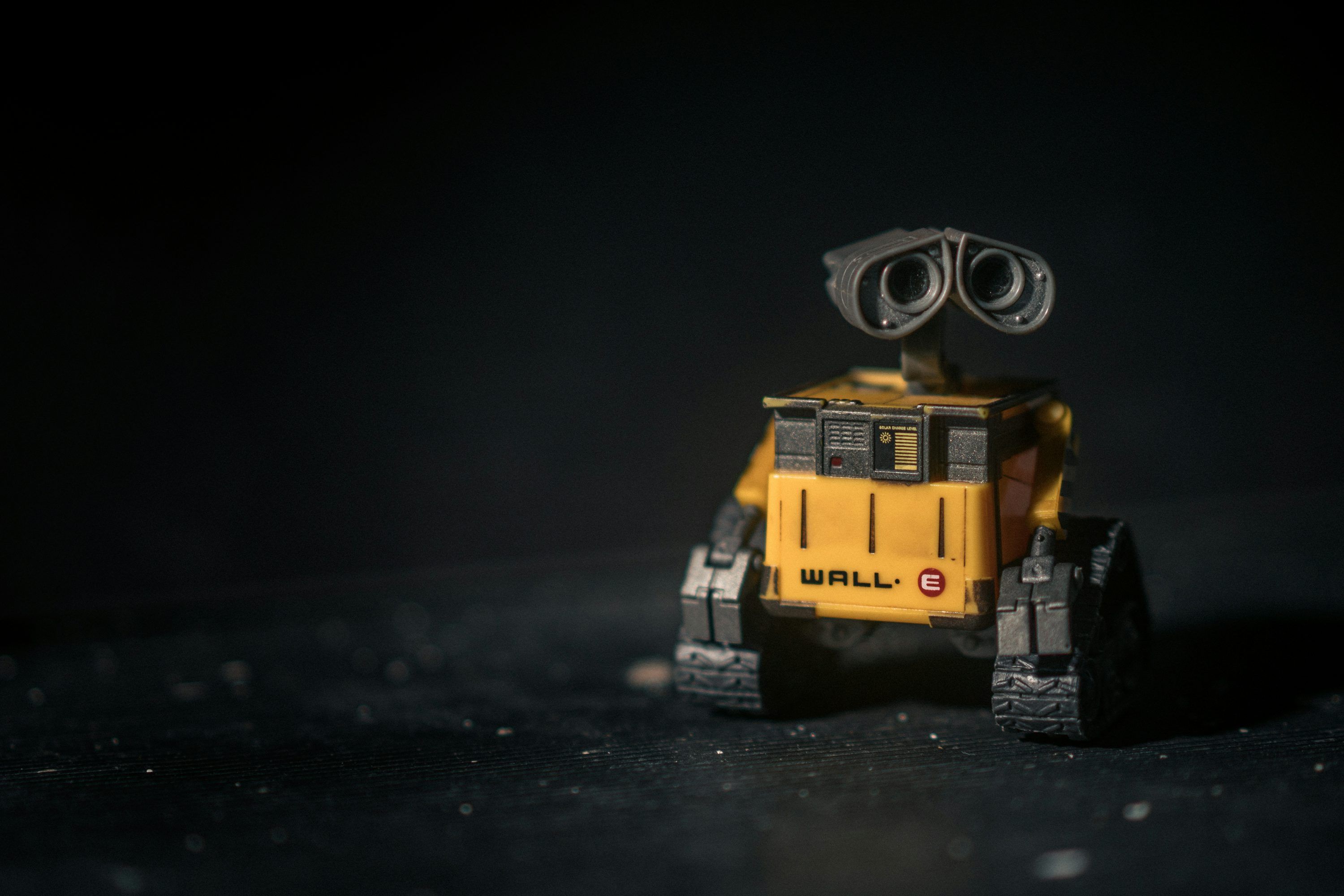 3000x2000 A small yellow and black robot on a black surface photo