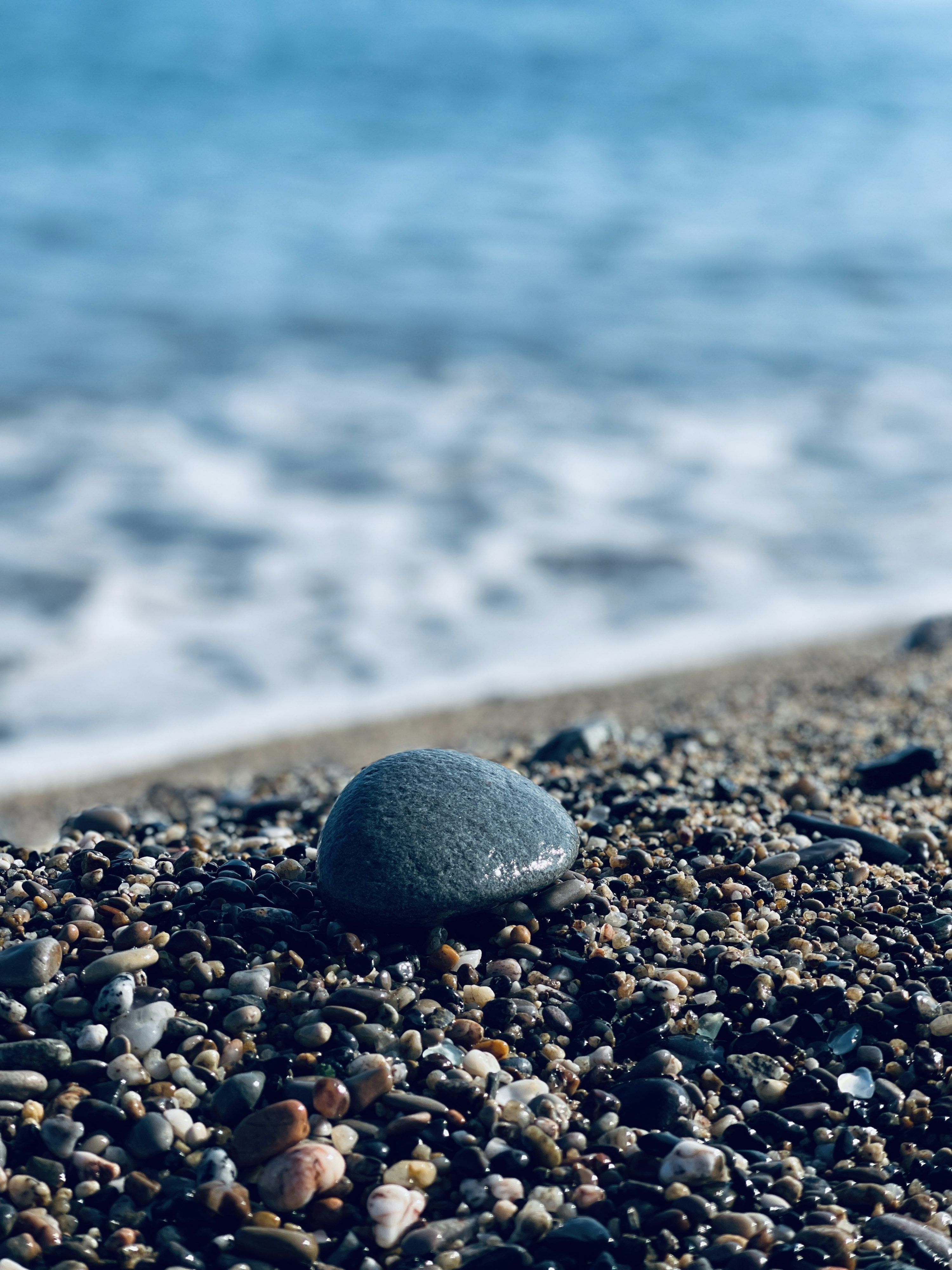 3000x4000 A rock sitting on top of a beach next to the ocean photo