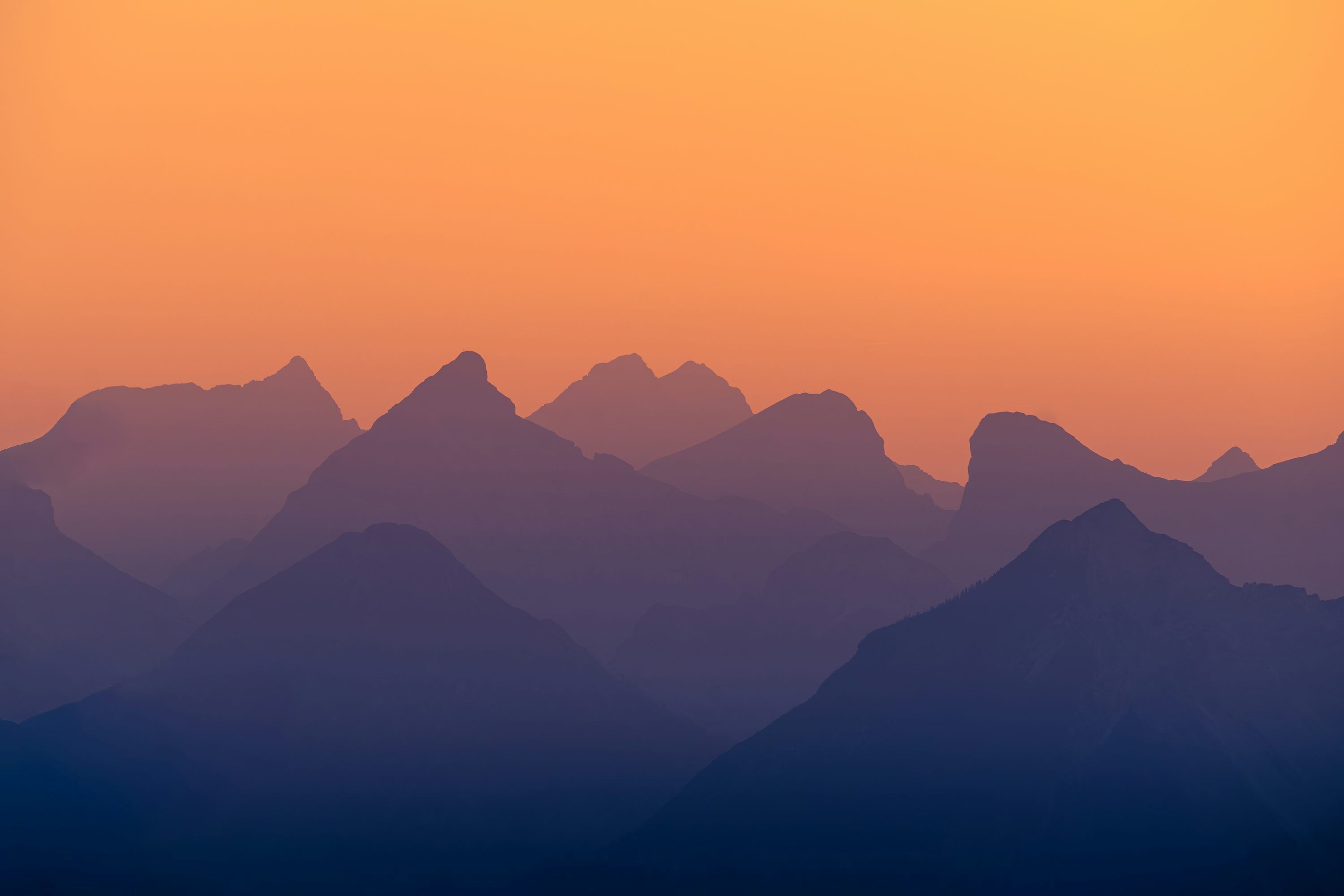 3000x2001 Layered mountain peaks at sunset with orange sky photo