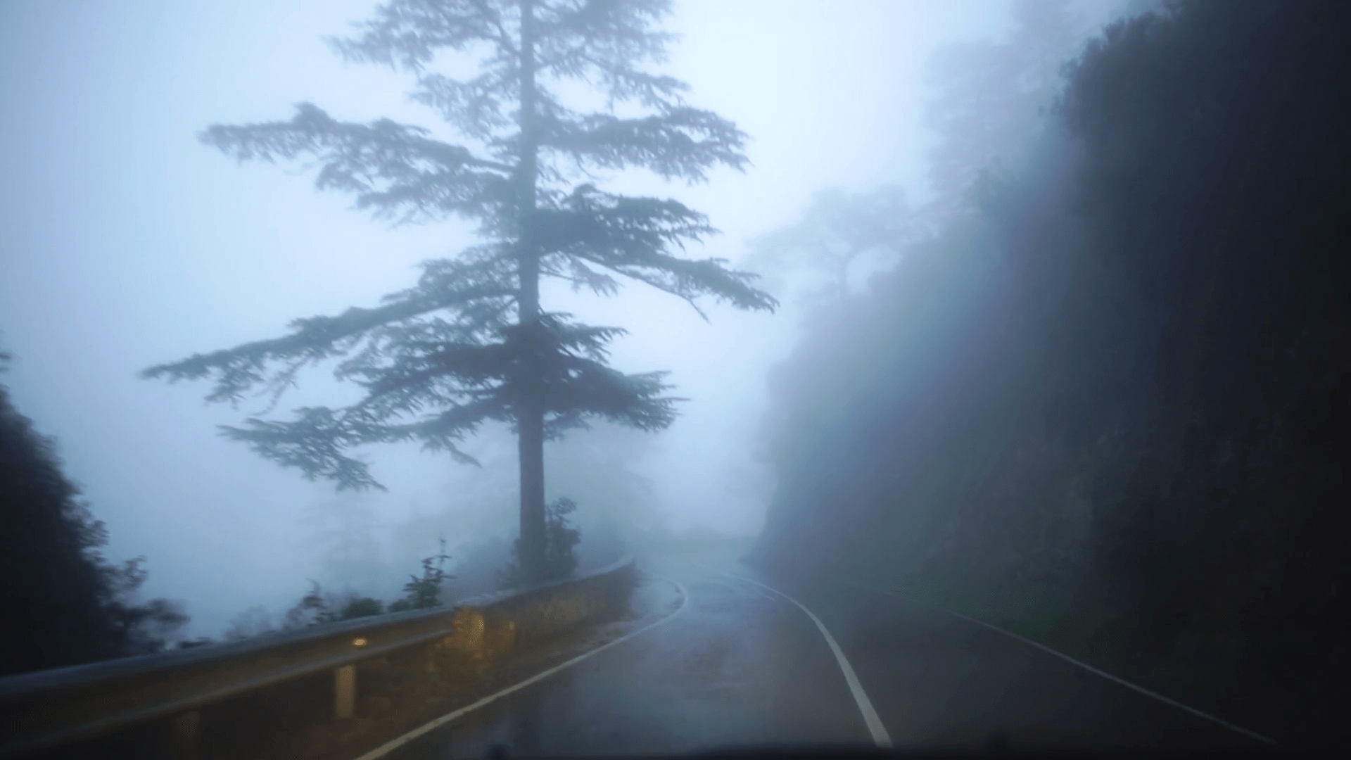 1920x1080 View of rainy foggy road with pictureque nature from driving car along roadside during journey. Cyprus. Slow motion