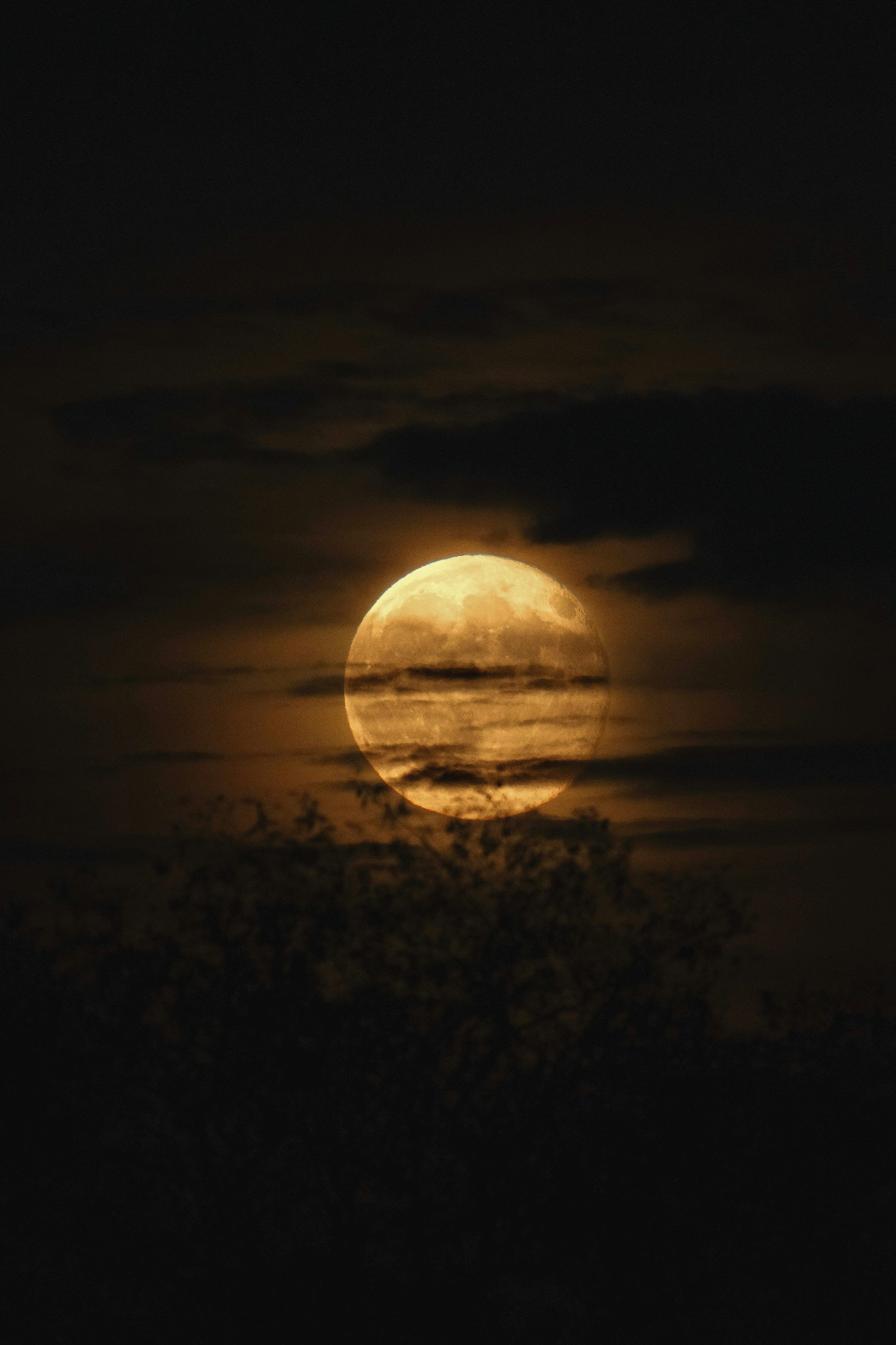 3000x4500 A bright full moon shines through dark clouds at night. photo