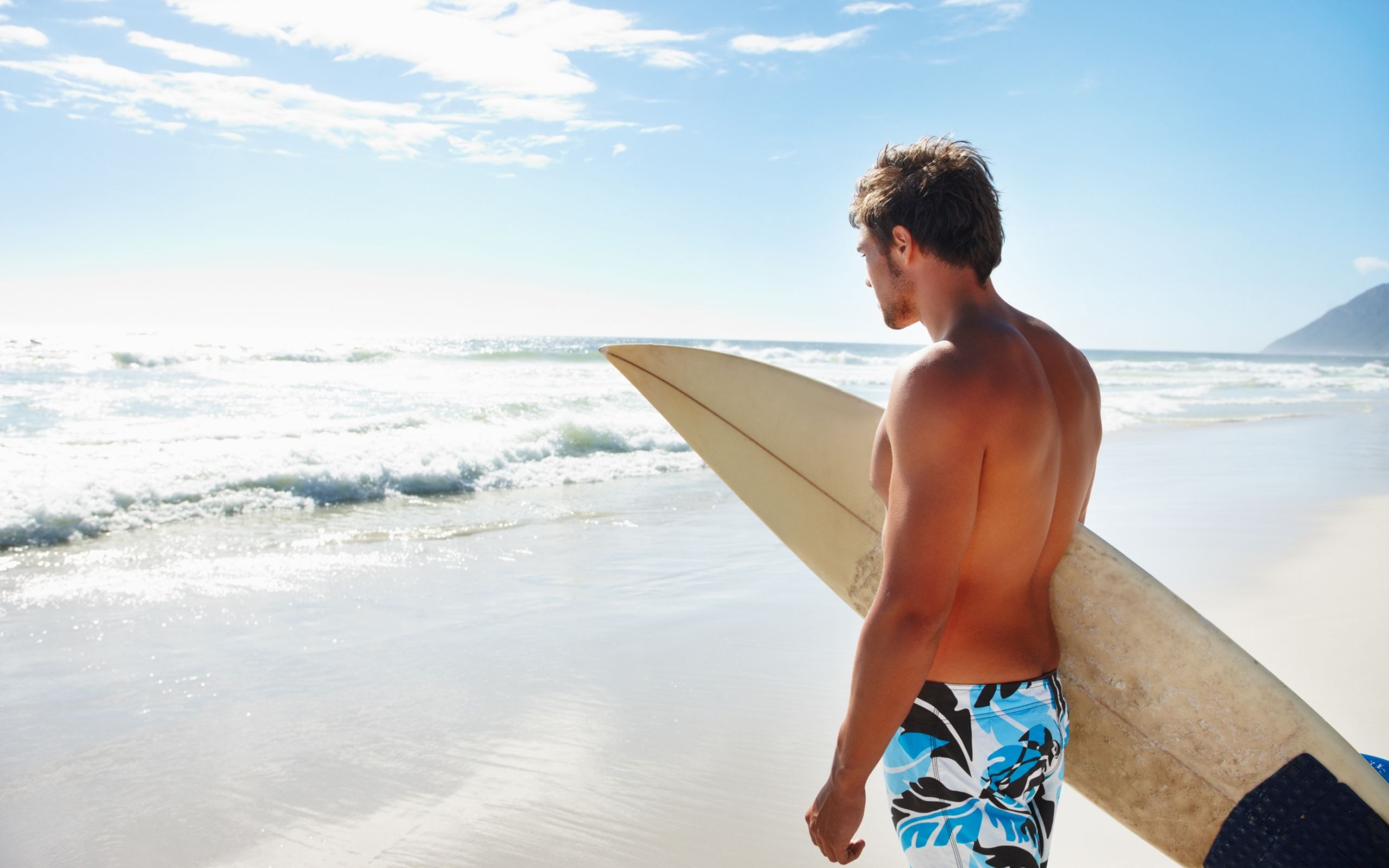 2560x1600 Wallpaper Man in Blue and White Board Shorts Holding White Surfboard on Beach During Daytime, Background Free Image