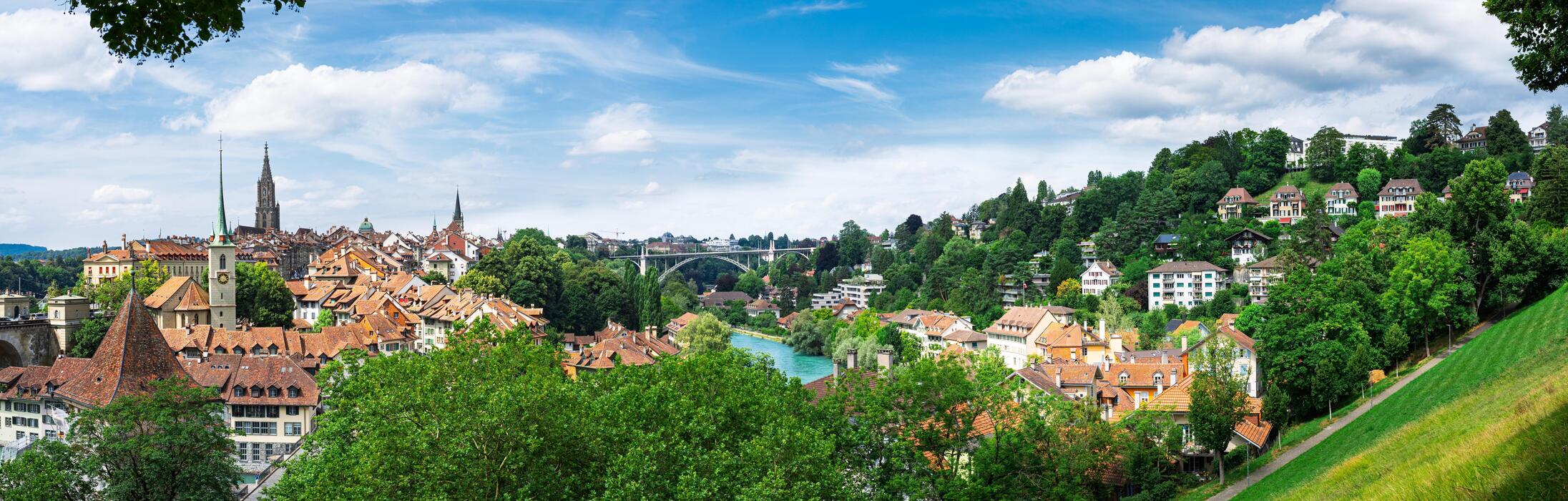 2192x700 Discover the charm of Bern, Switzerland in this panoramic view. Experience the blend of historic architecture, green landscapes, and the serene Aare River, ideal for travel marketing