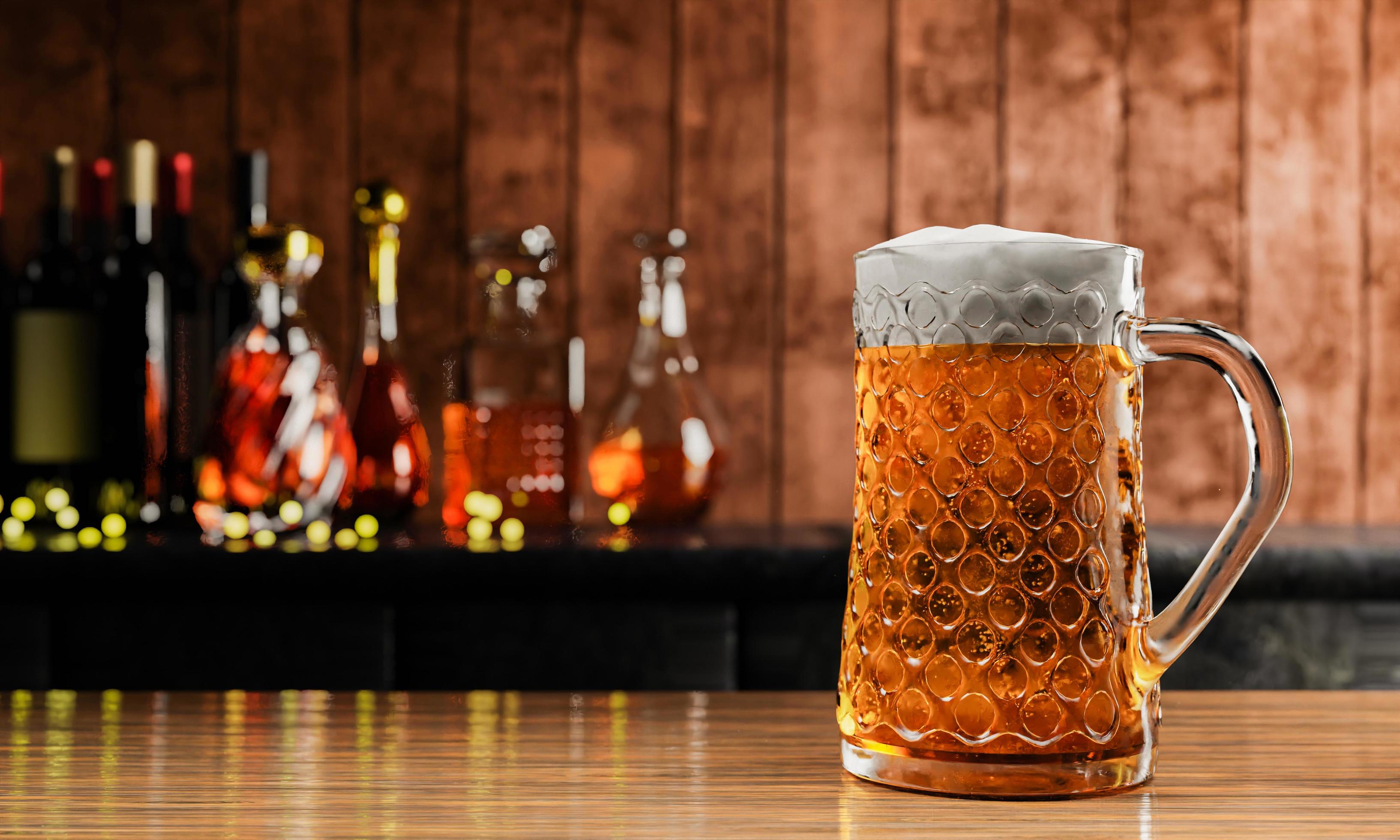 3267x1960 Draft or craft beer in tall clear glass. With cold steam, White beer foam placed on a wooden floor, behind the background is a bottle of wine, whiskey, brandy at the restaurant