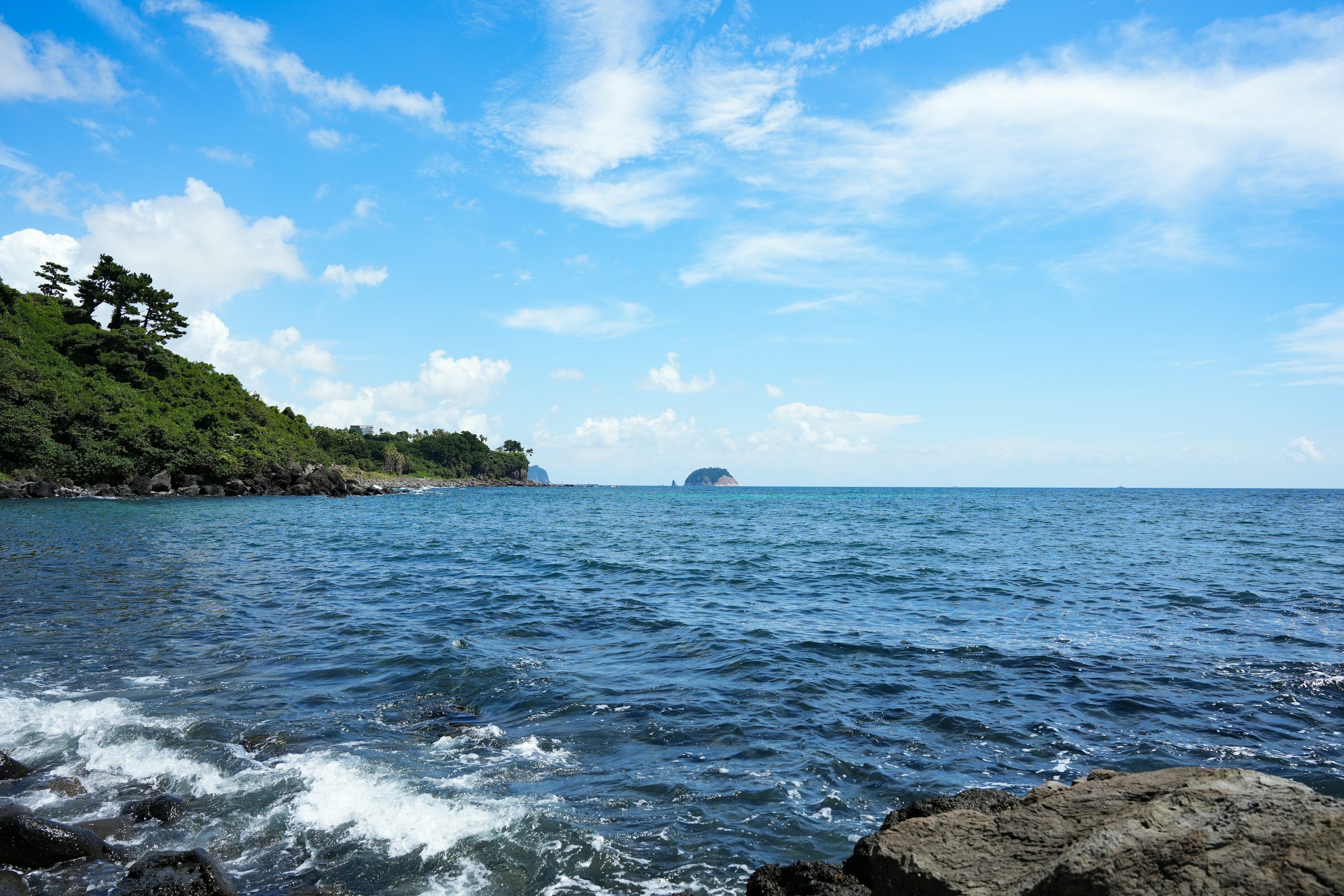3000x2000 Blue ocean with rocky shore and distant island. photo