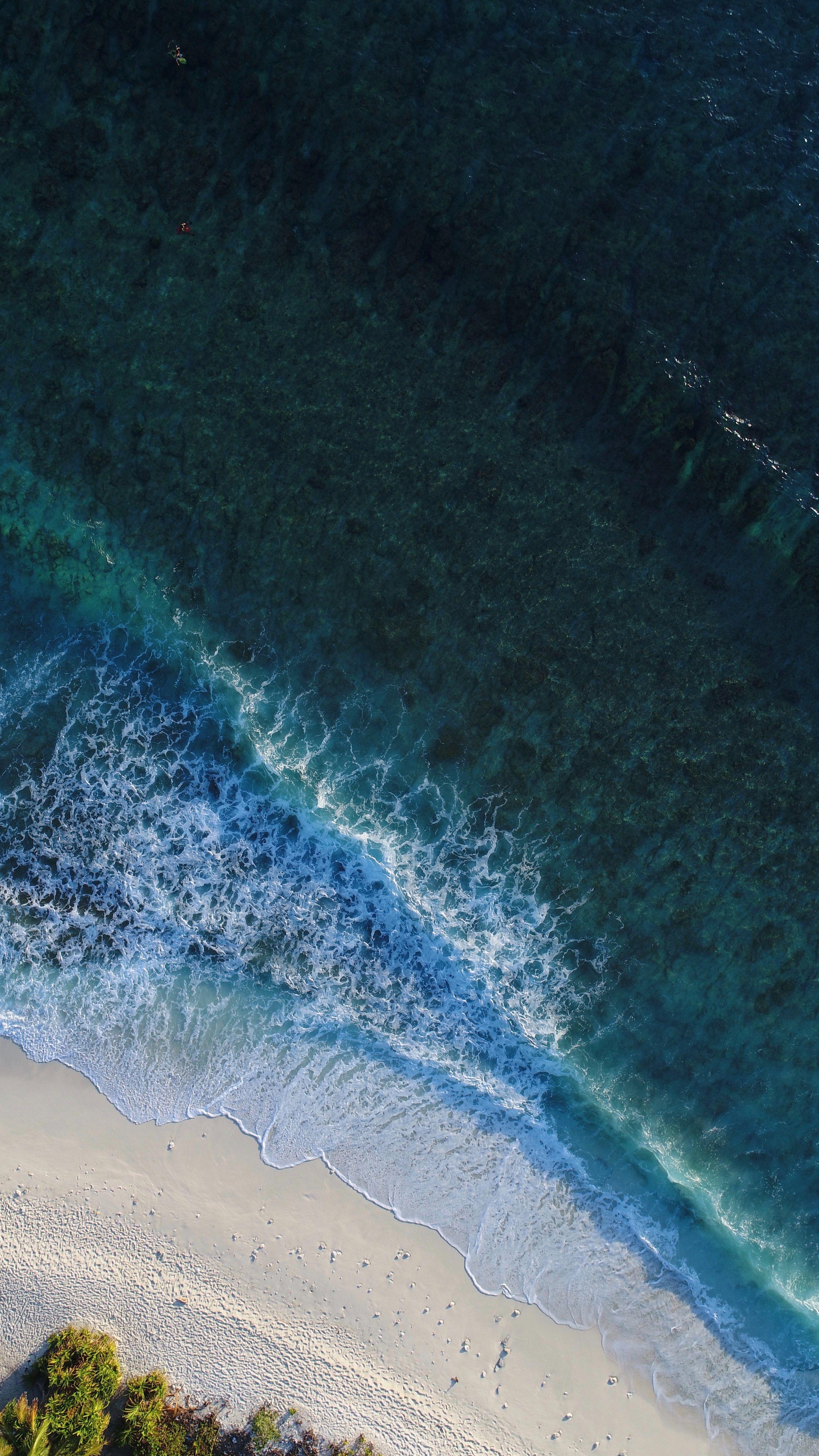 3078x5472 drone aerial view of ocean waves washing on the sand beach at