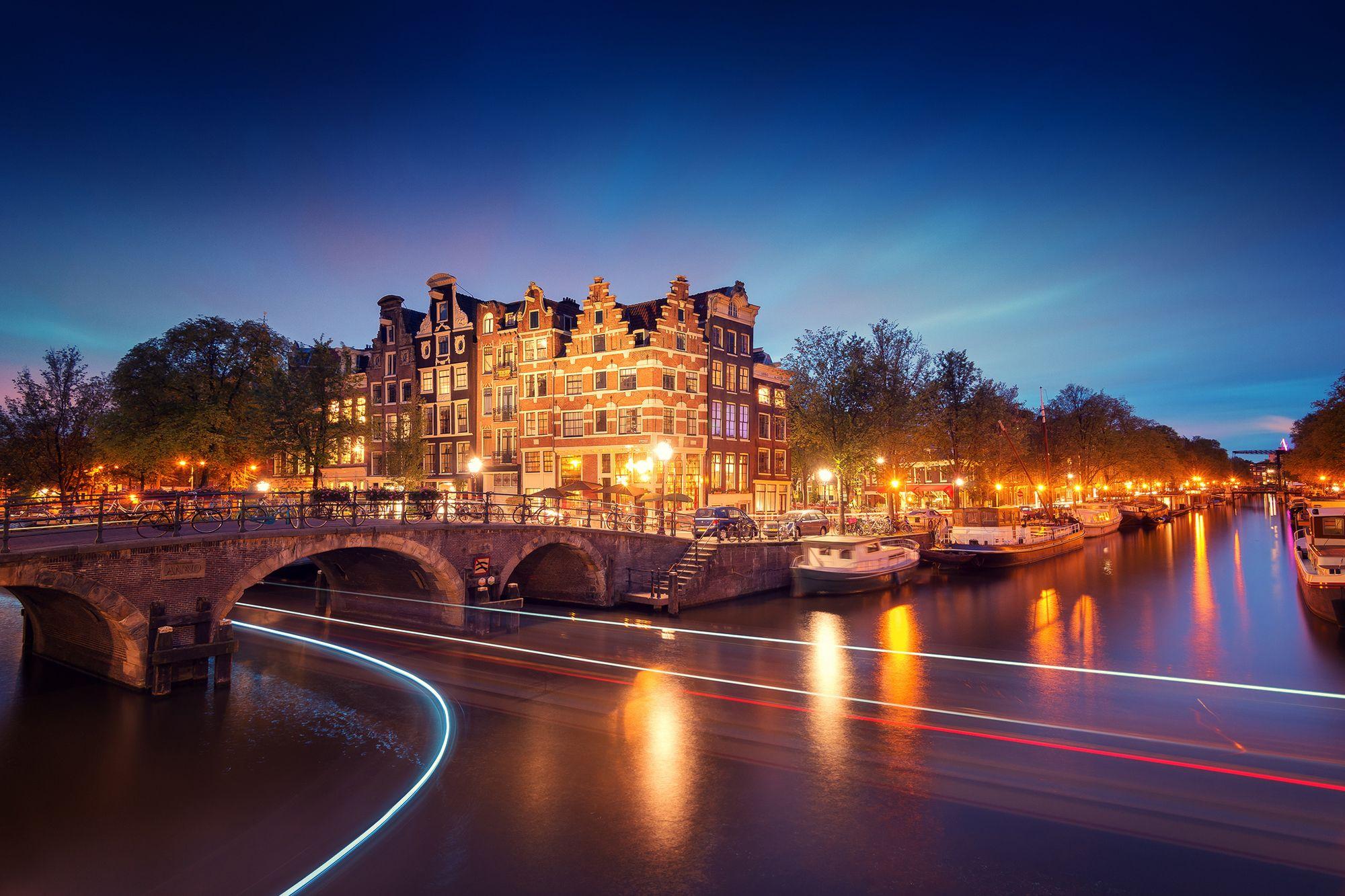 2000x1333 Amsterdam Netherlands Holland city night bridge canal lights exposure light lighting lights river boats trees wallpaperx1333