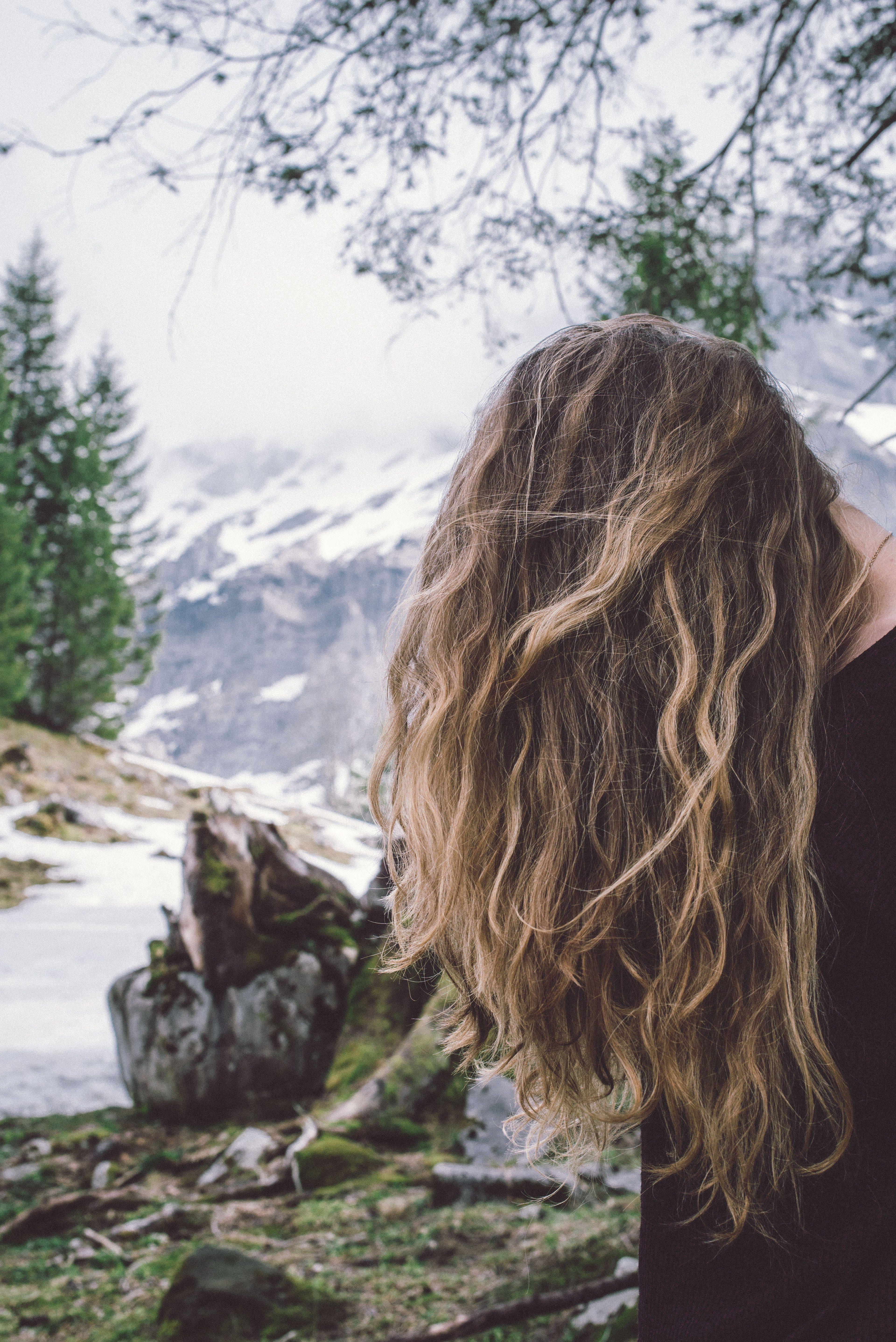 3840x5752 curly hair covers a womans face in a mountain landscapewind