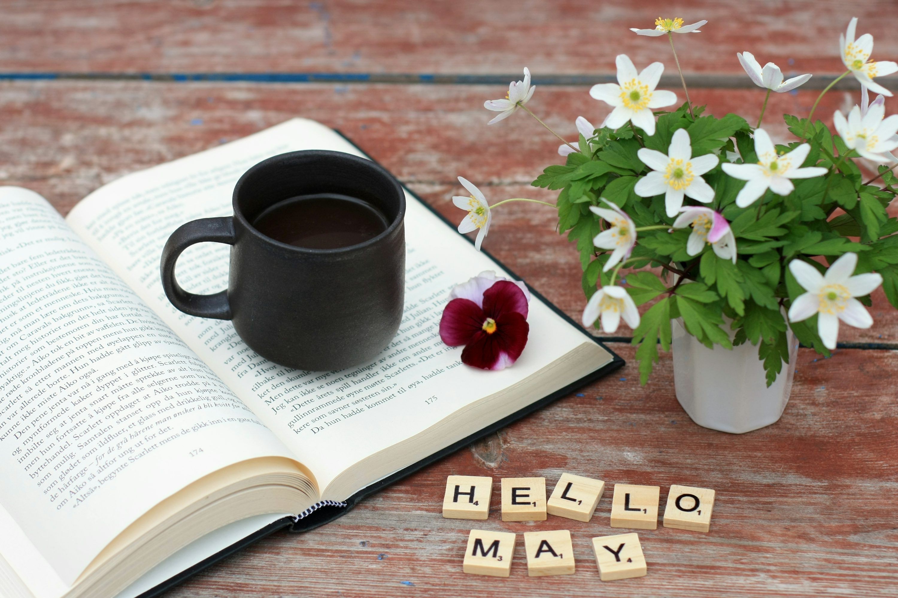 3000x2000 A cup of coffee next to a book and flowers photo