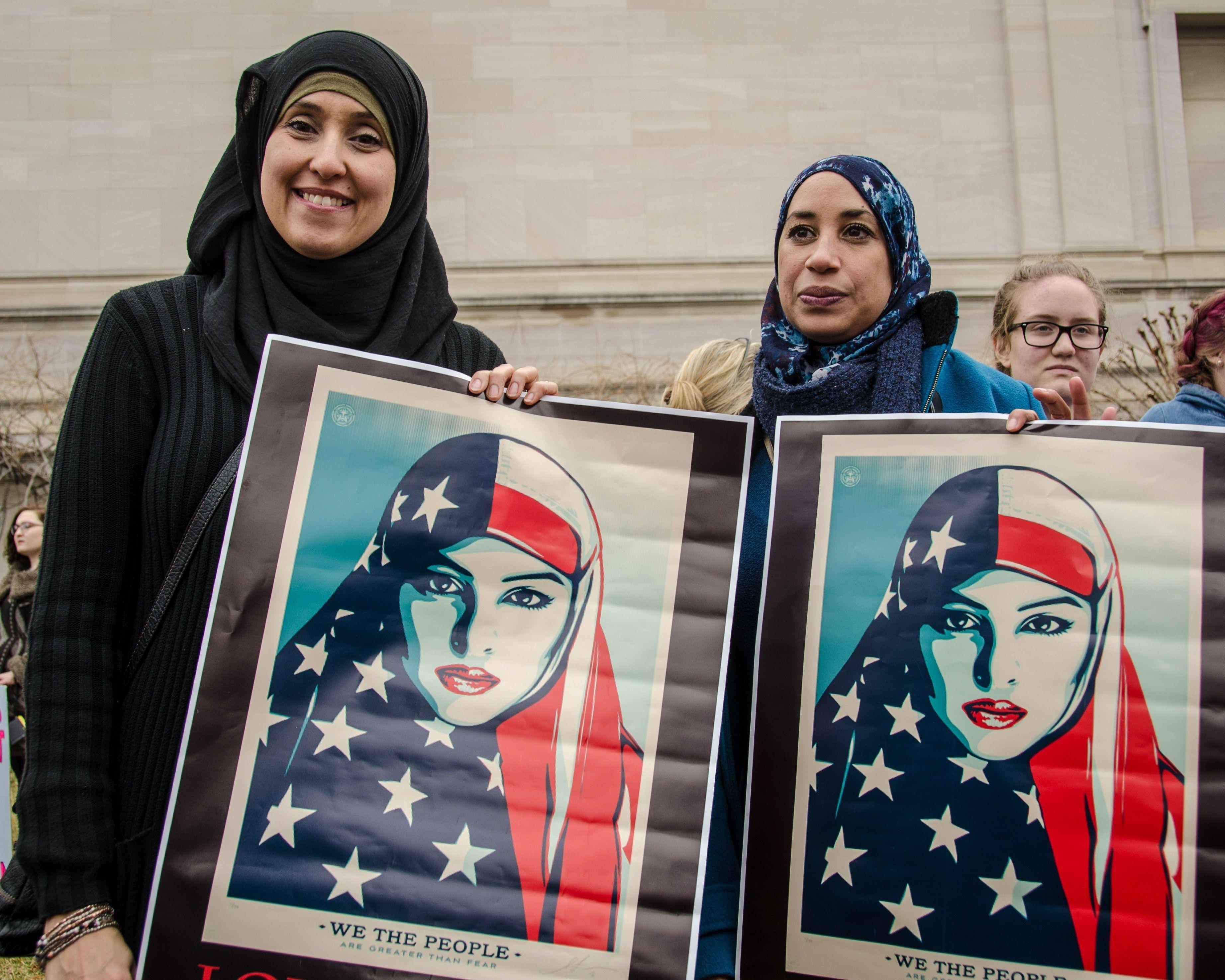 3687x2950 two women in hijabs hold posters of an american muslim woman at a