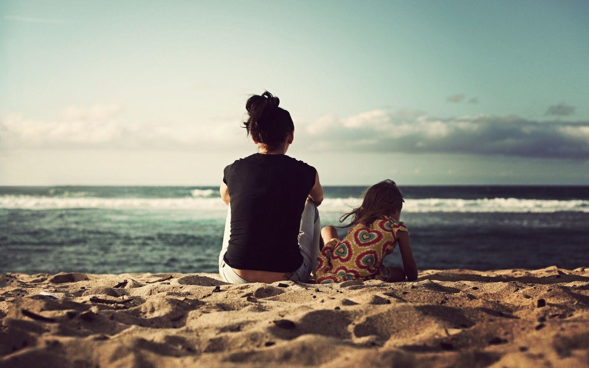 1920x1200 A woman and her daughter sitting in the sand on the beach
