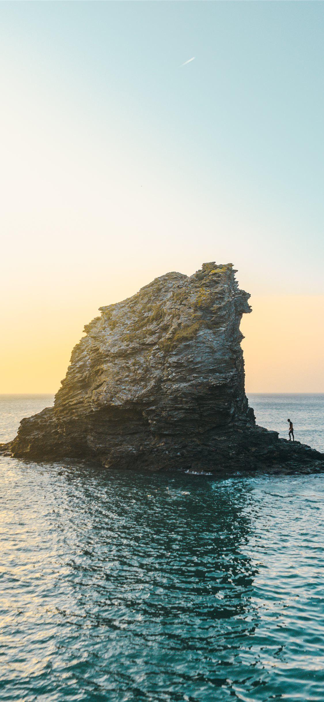 1125x2436 two people standing on rock formation surrounded b. iPhone 11