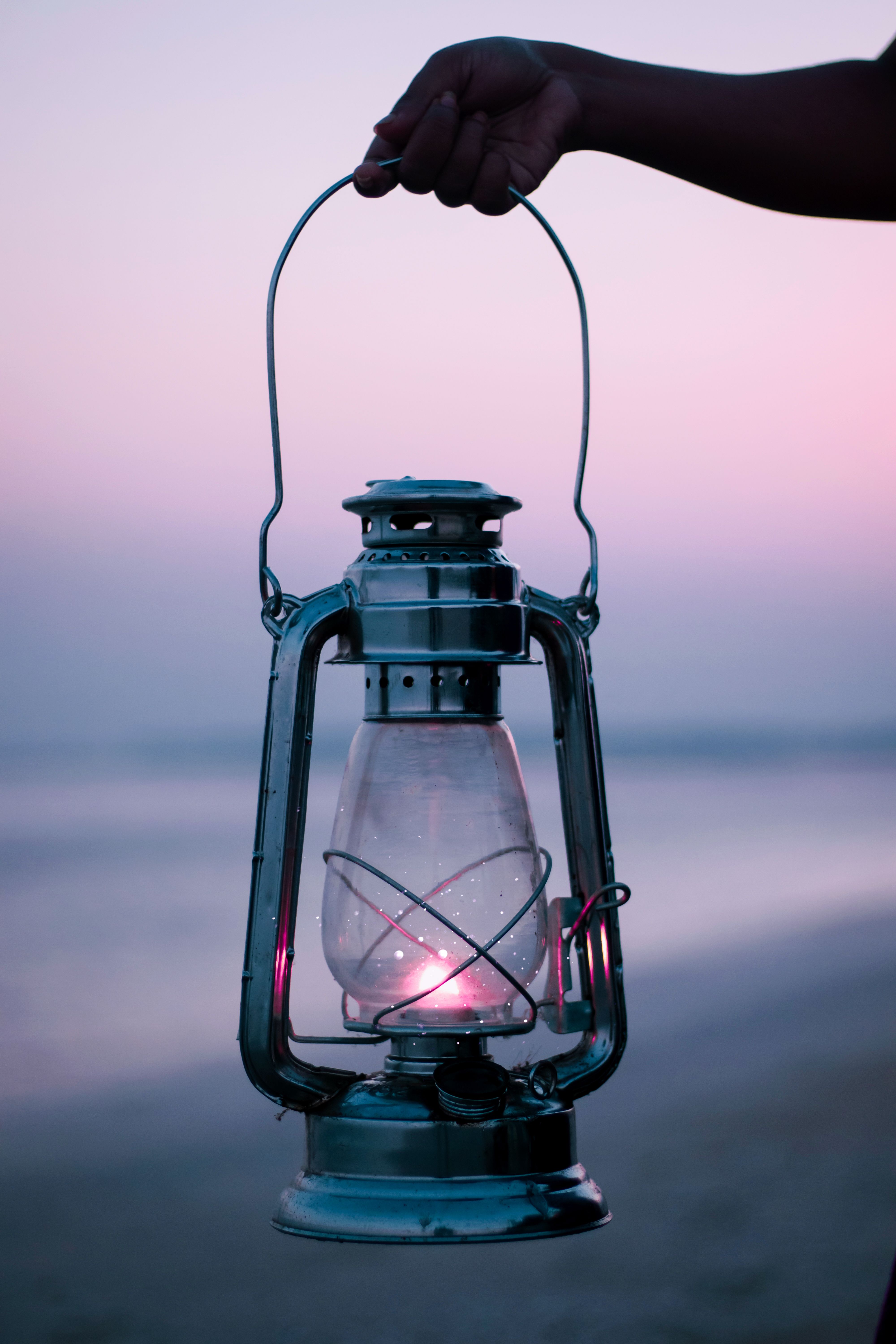 4000x6000 Woman Holding a Kerosene Lamp at Dusk on a Beach · Free
