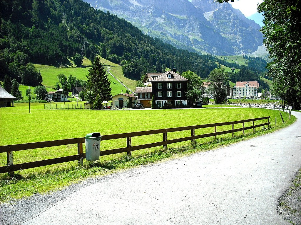 1024x768 A dirt road with a fence and a house in the background