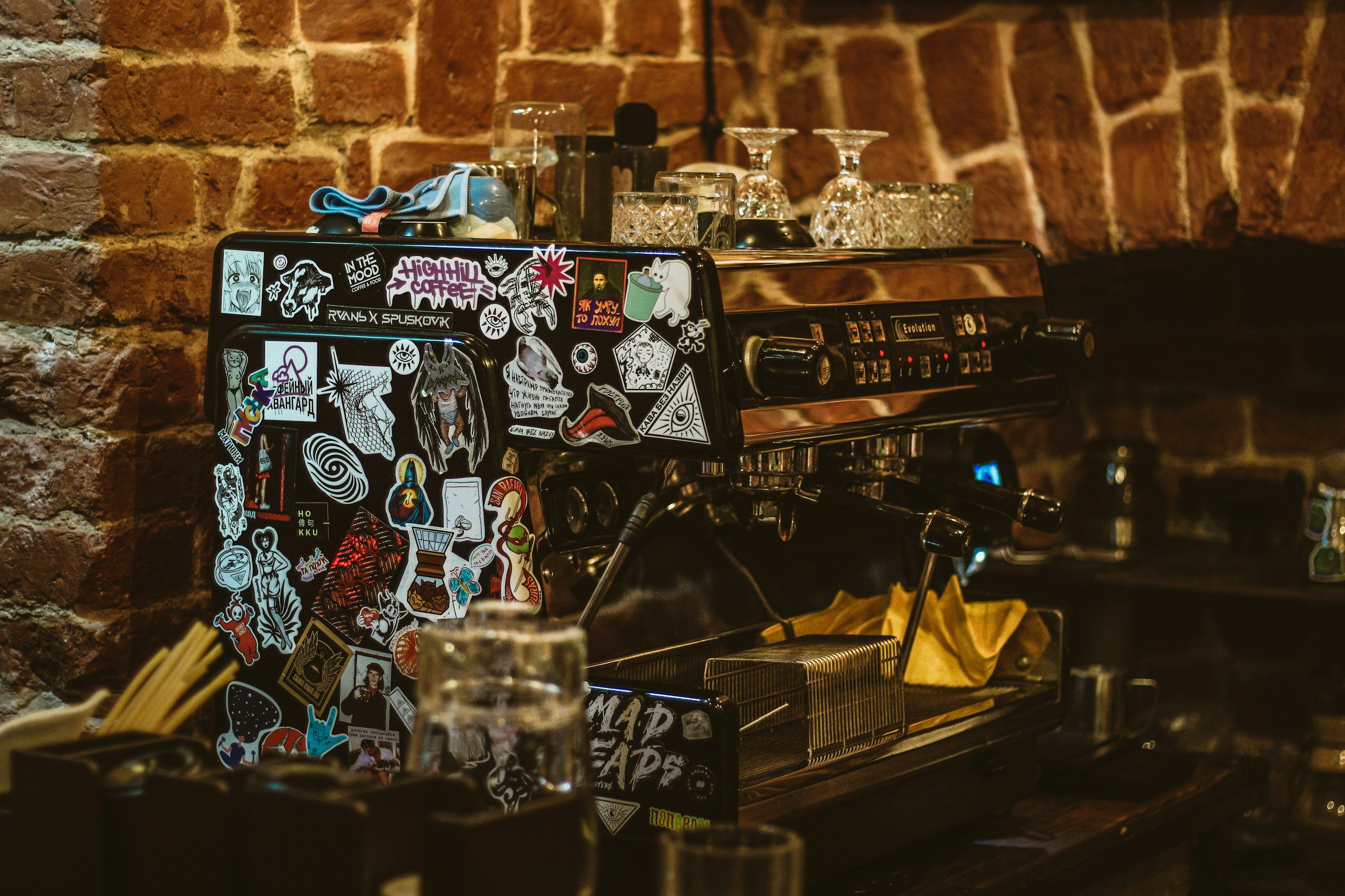 3000x2000 Coffee machine with stickers stands against brick wall. photo