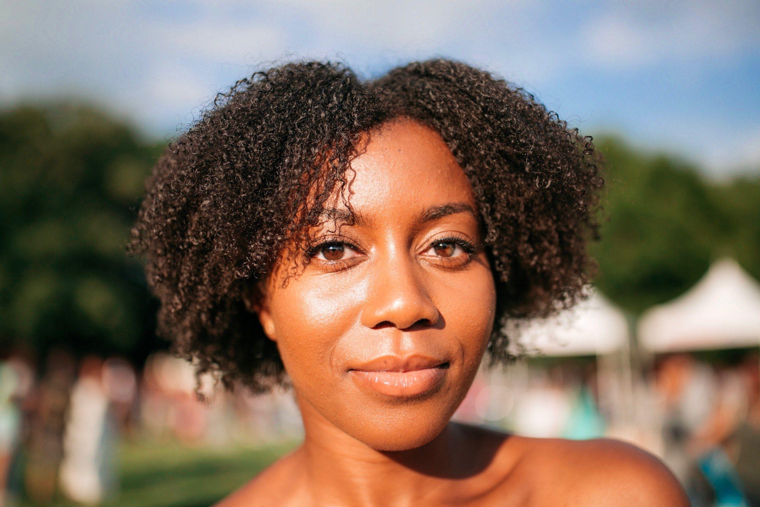 2560x1707 happy woman with curly natural hair smiling softly outsidecurlfest
