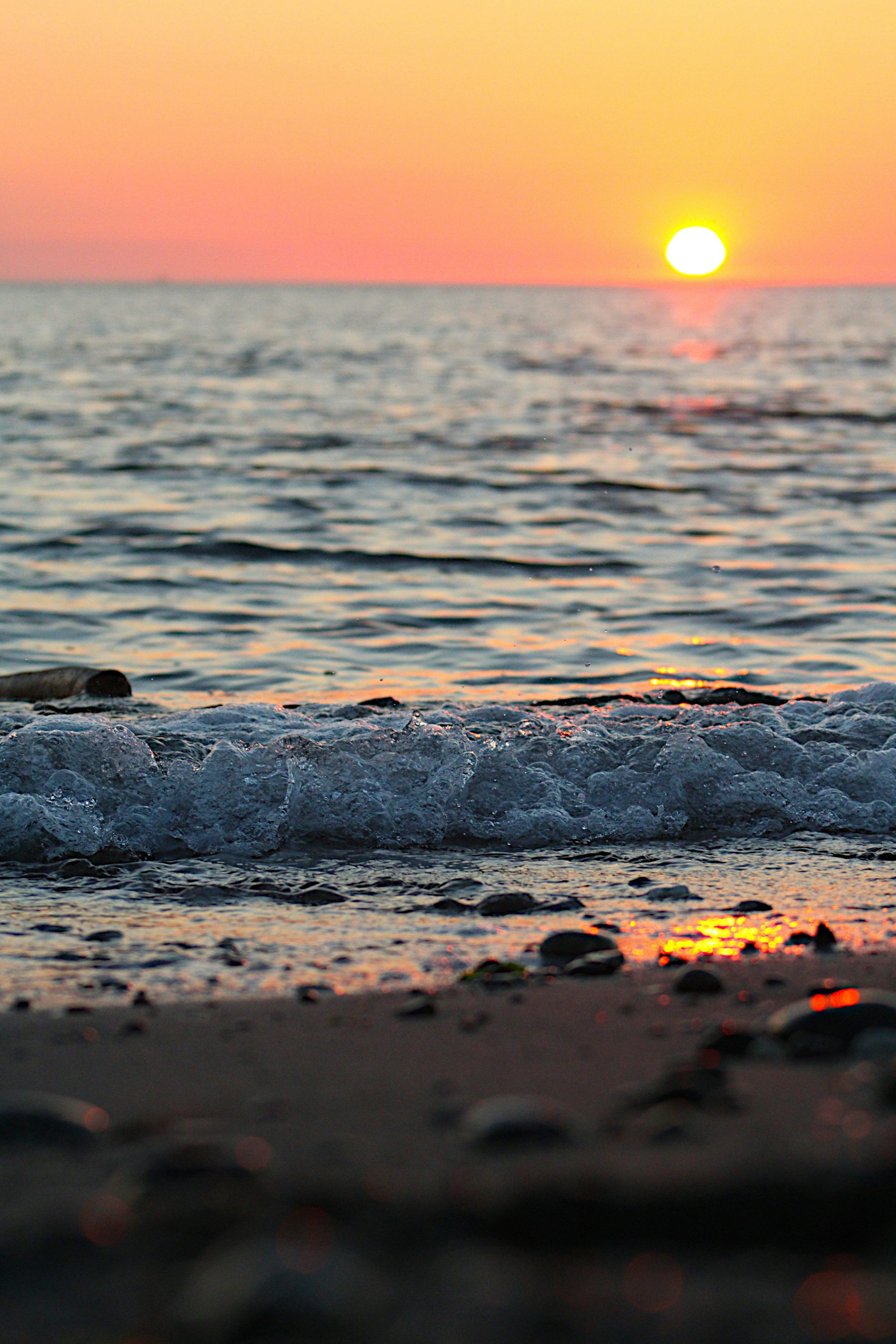 3000x4500 The sun is setting over the water at the beach photo
