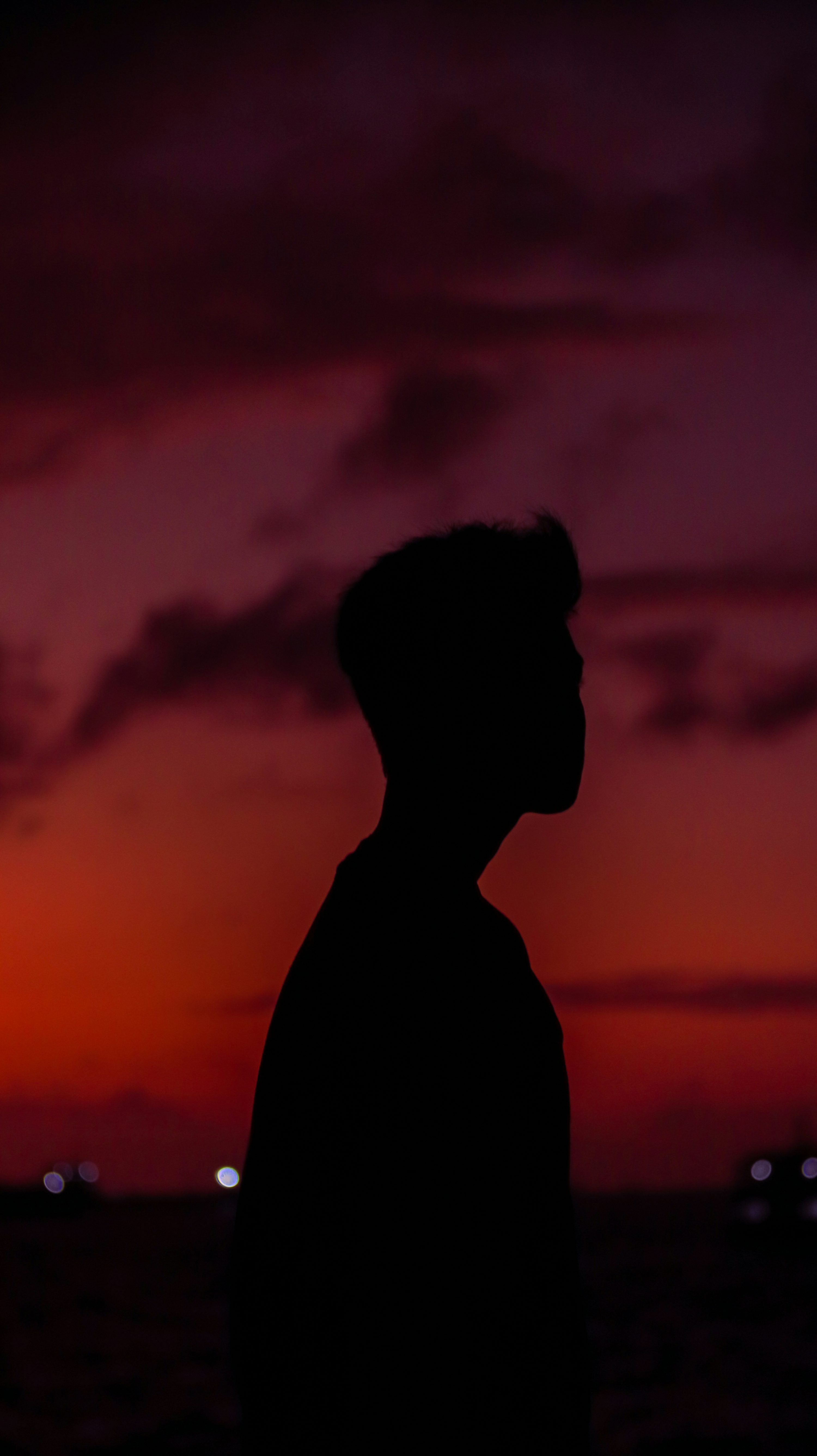 3000x5344 A silhouette of a man standing in front of a sunset photo