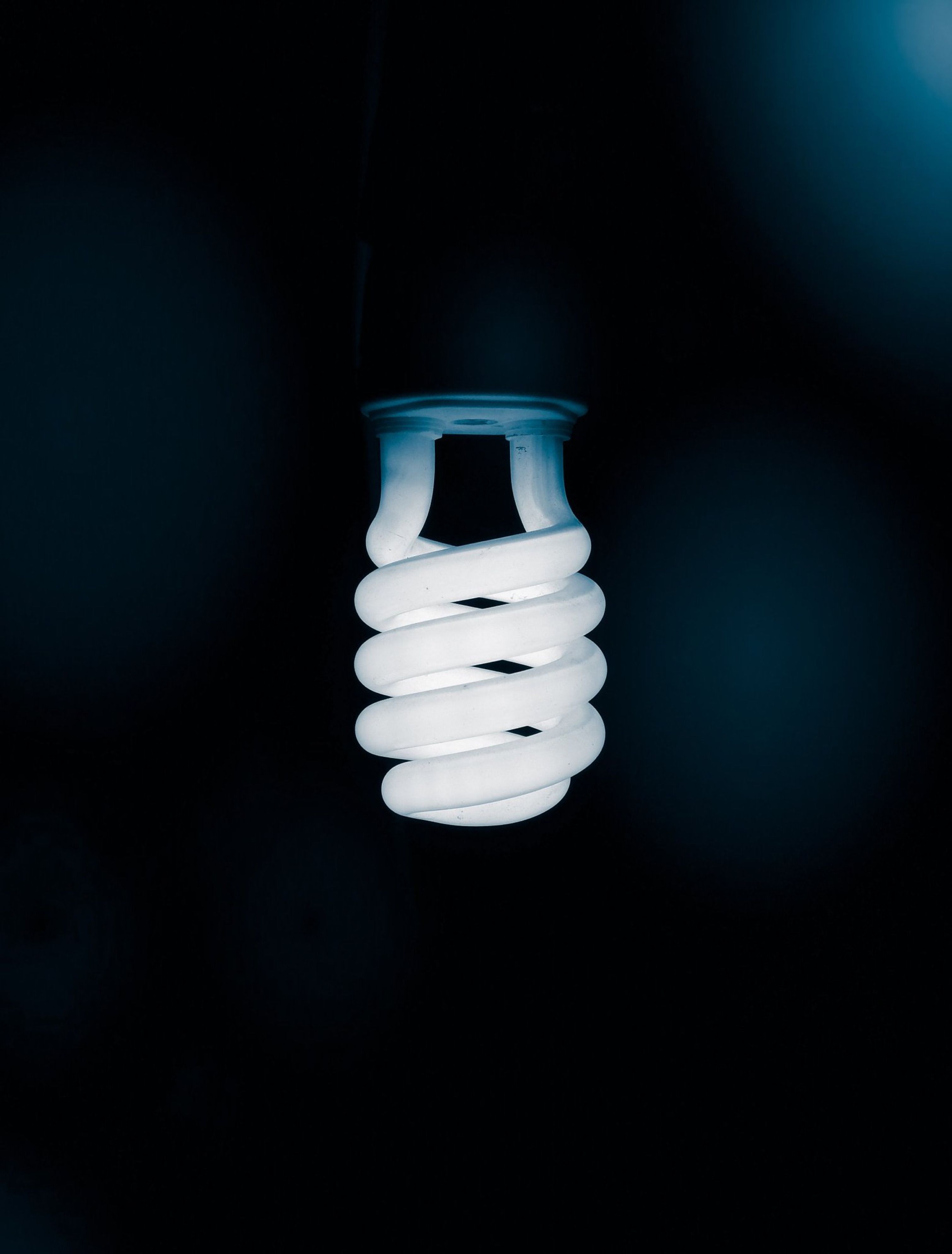 3018x3974 Minimalist Spiral Fluorescent Light Bulb Against Dark Background · Free