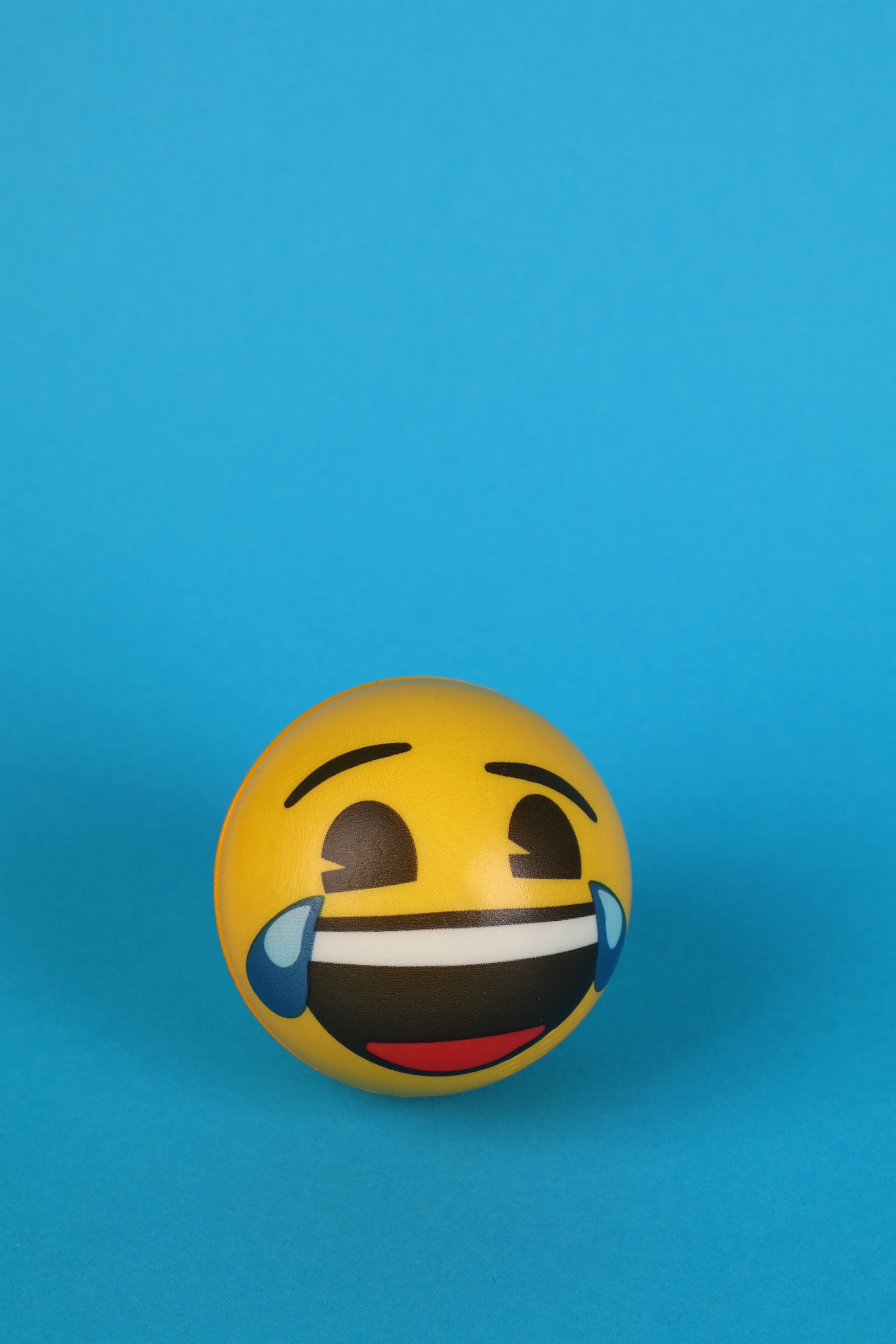 4000x6000 A Laughing Emoji with tears over Blue Surface · Free
