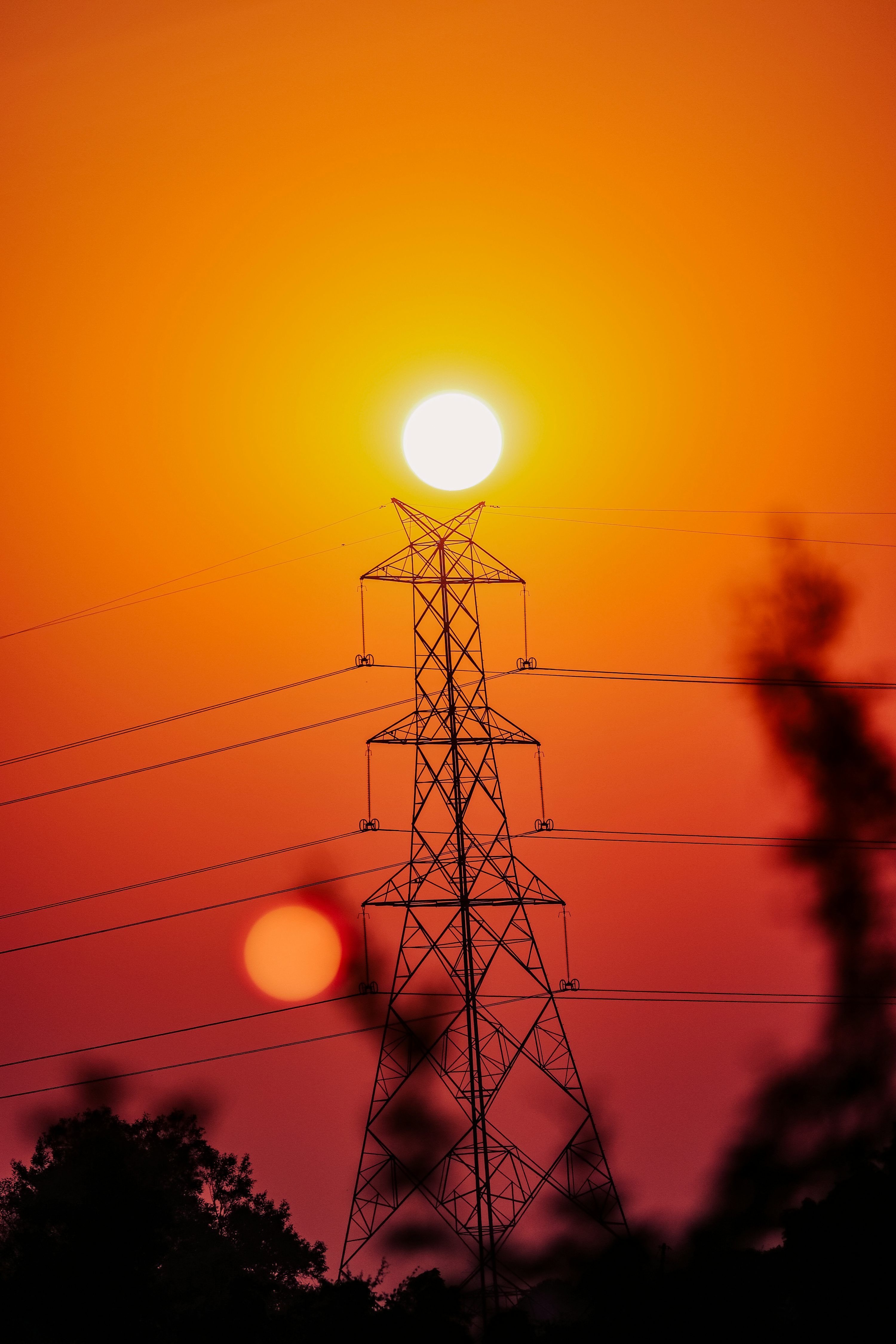 3000x4500 The sun is setting behind an electric tower photo