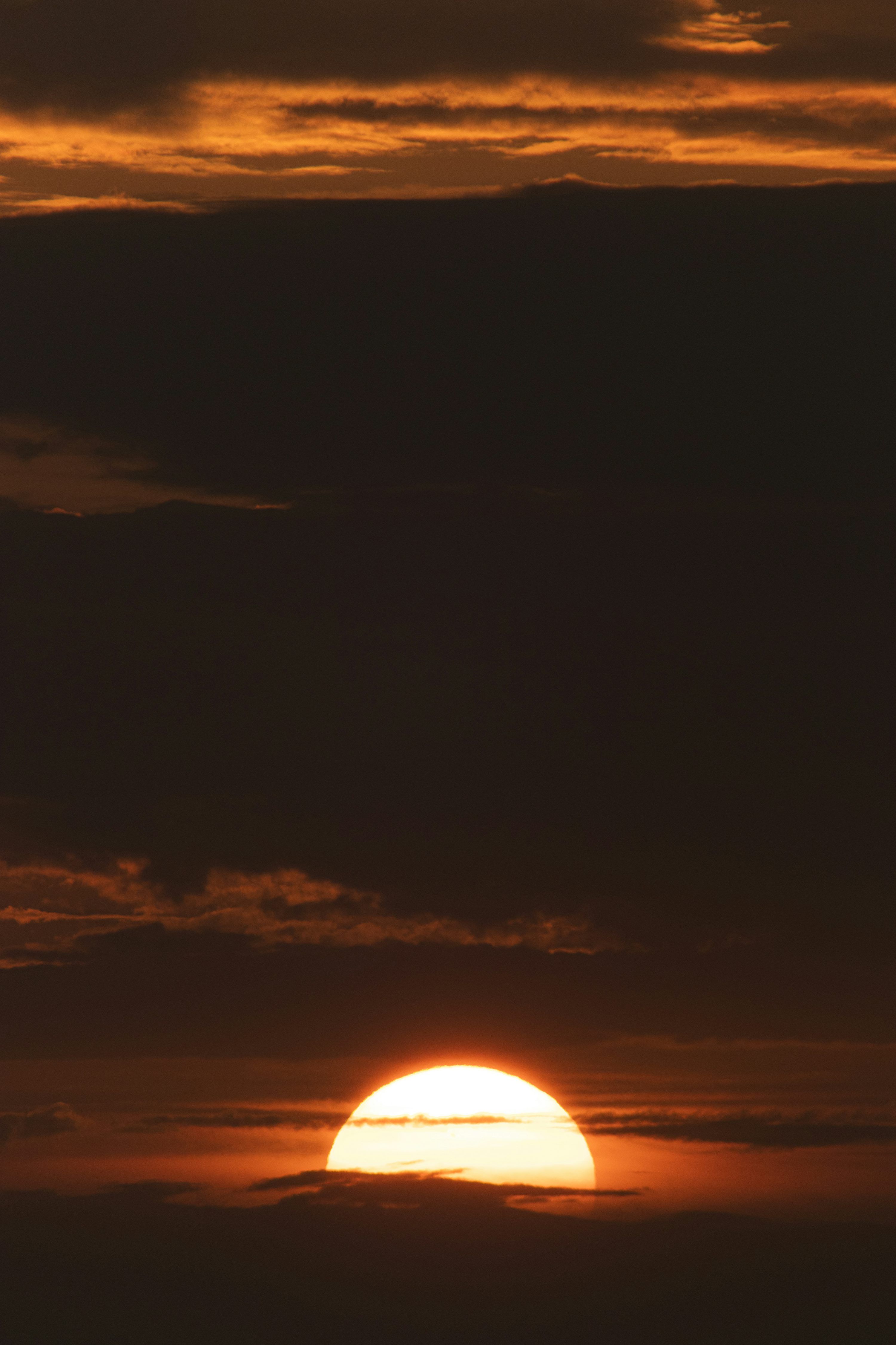 3000x4500 The sun is setting over the horizon of a cloudy sky photo