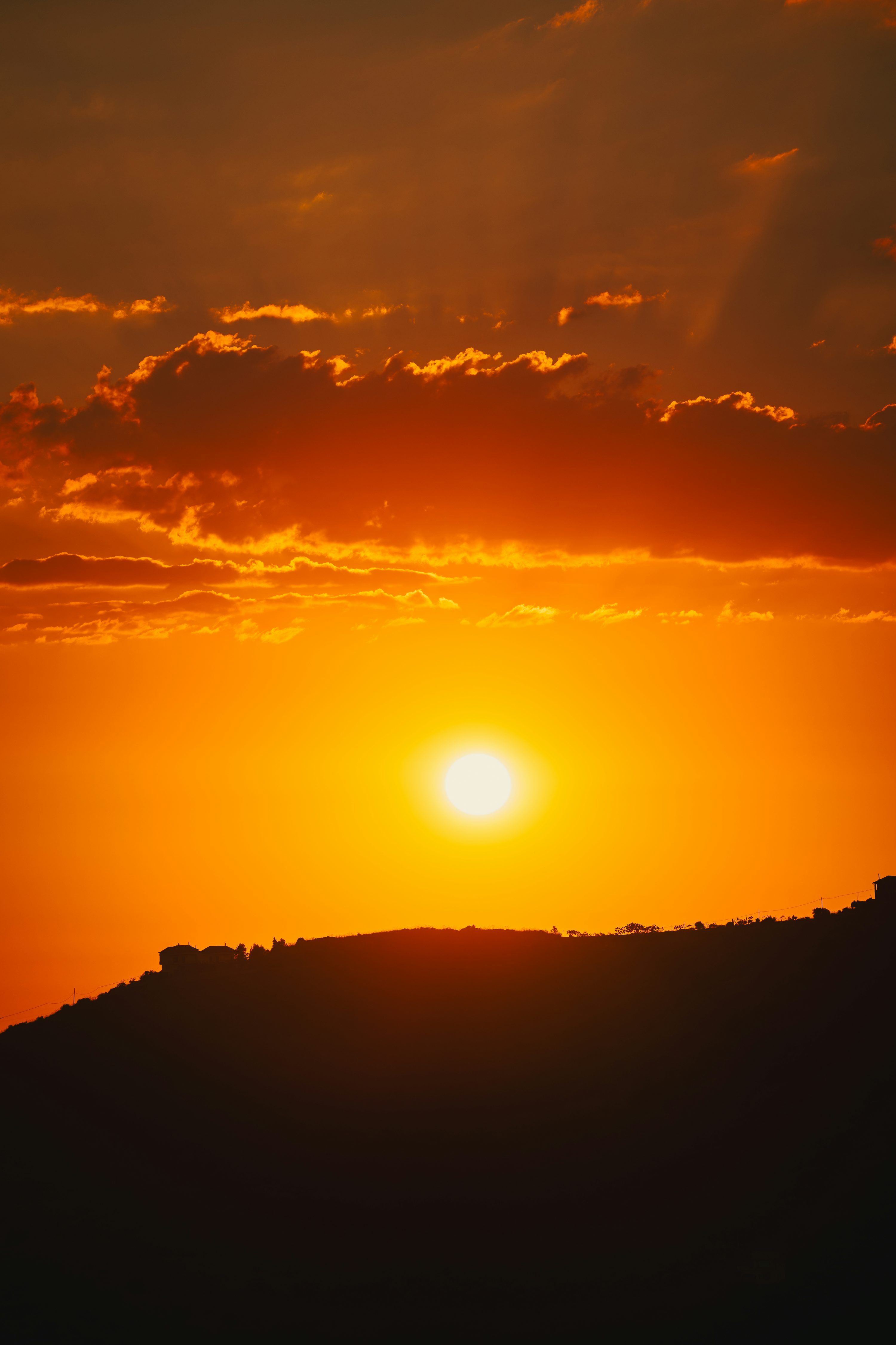 3000x4500 The sun is setting over the horizon of a hill photo