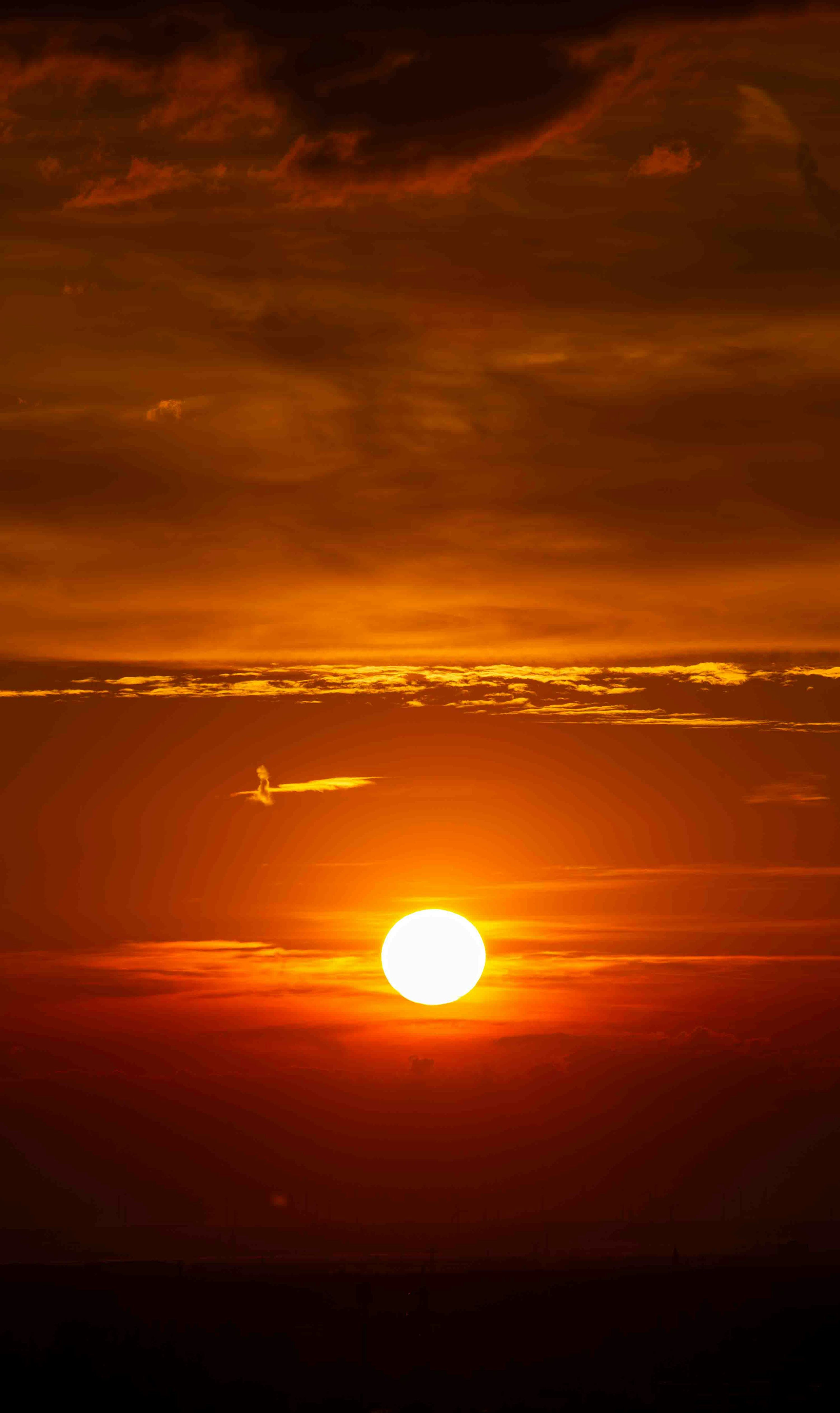 3000x5044 The sun is setting over the horizon of the ocean photo