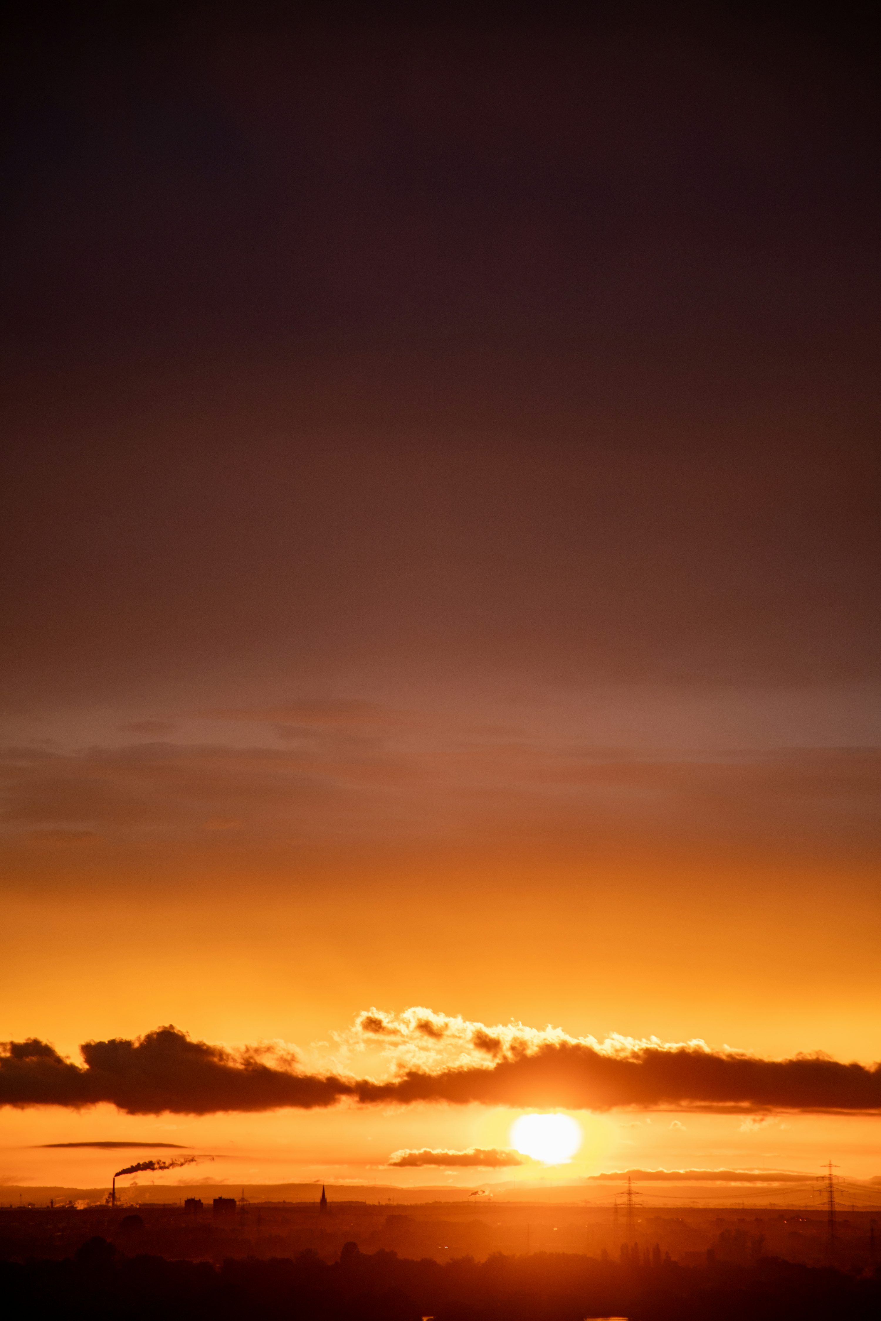 3000x4500 The sun is setting over the horizon of a city photo