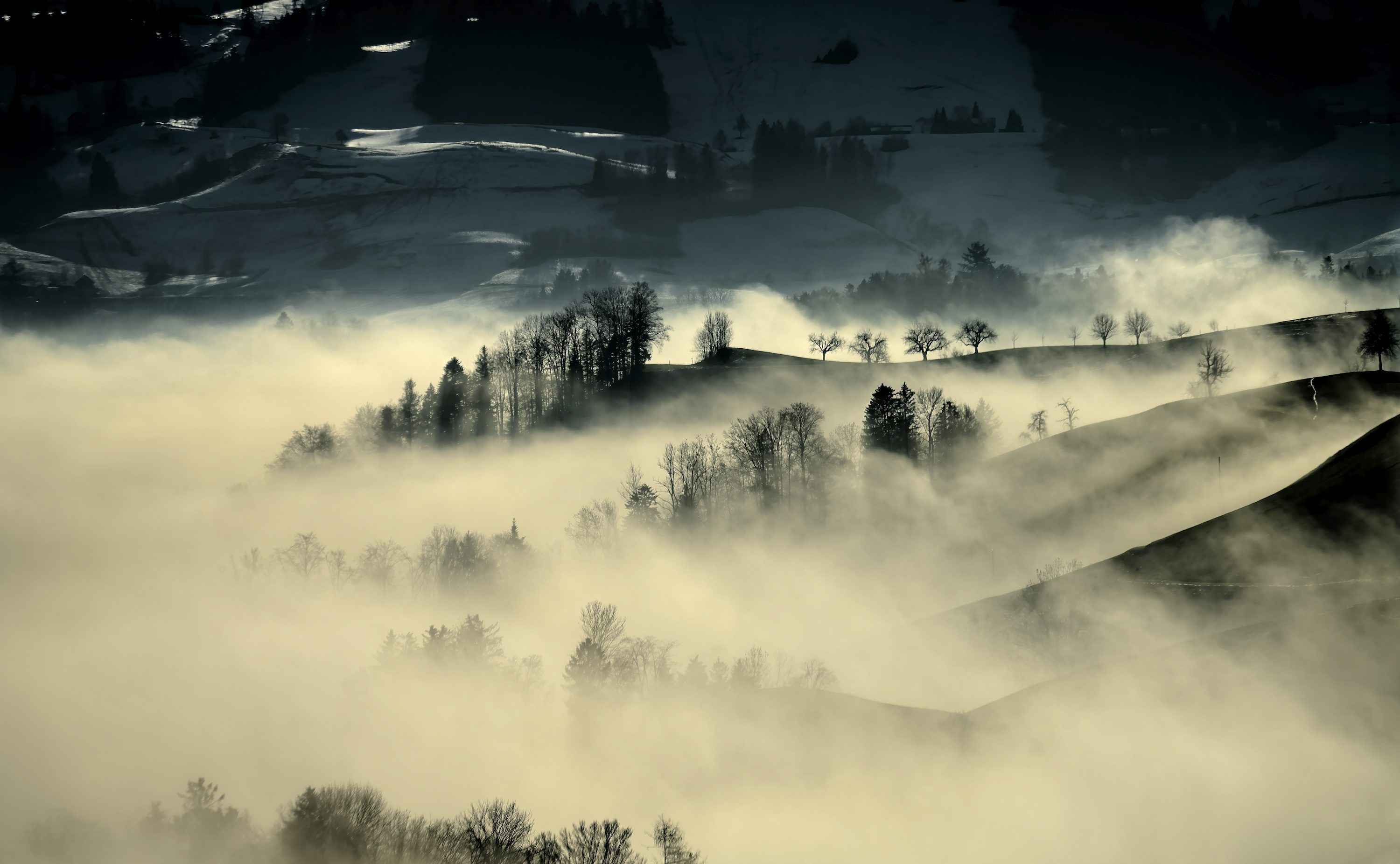 3000x1851 A black and white photo of a mountain covered in fog photo