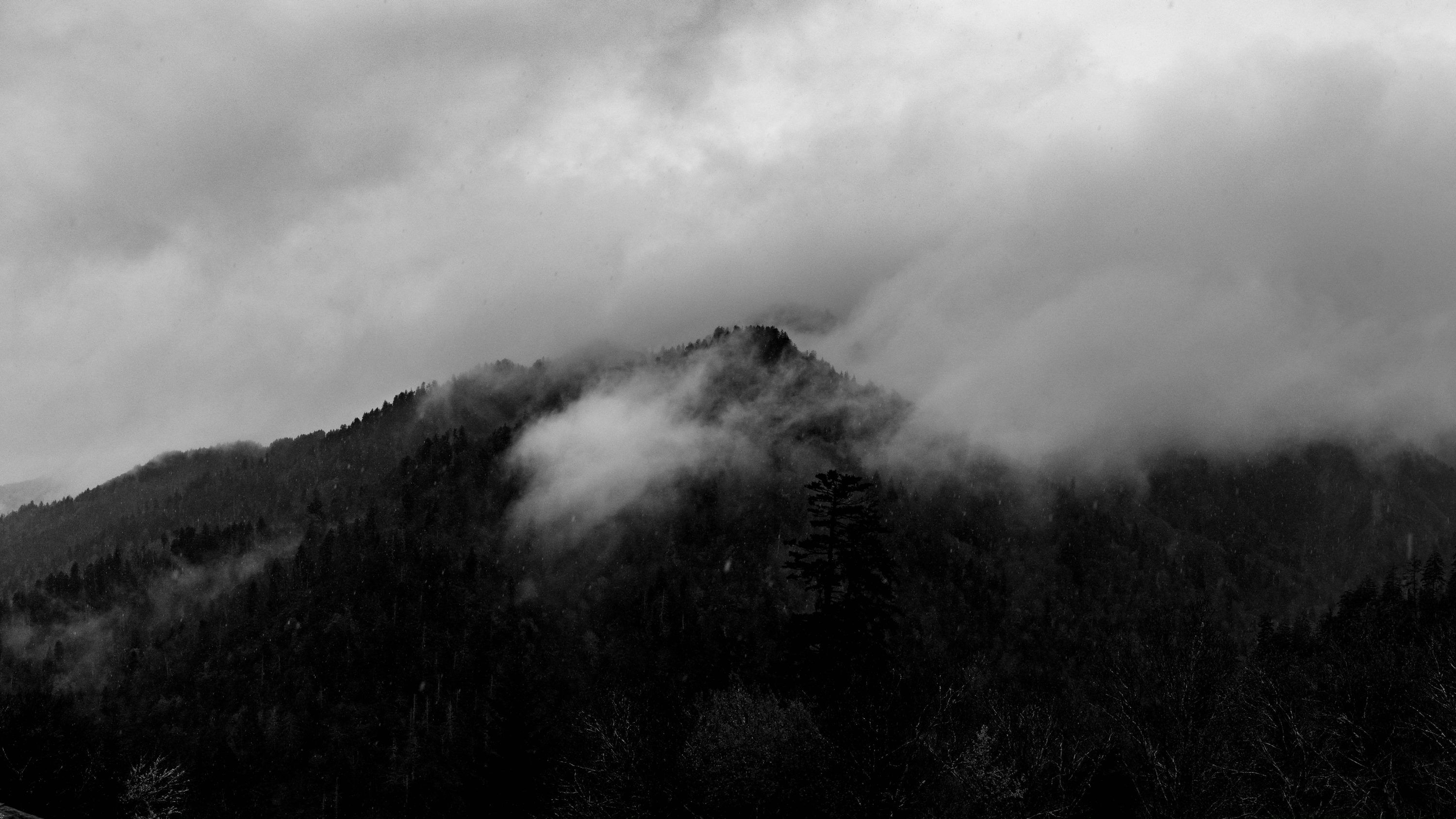 3000x1688 A black and white photo of a mountain covered in clouds photo