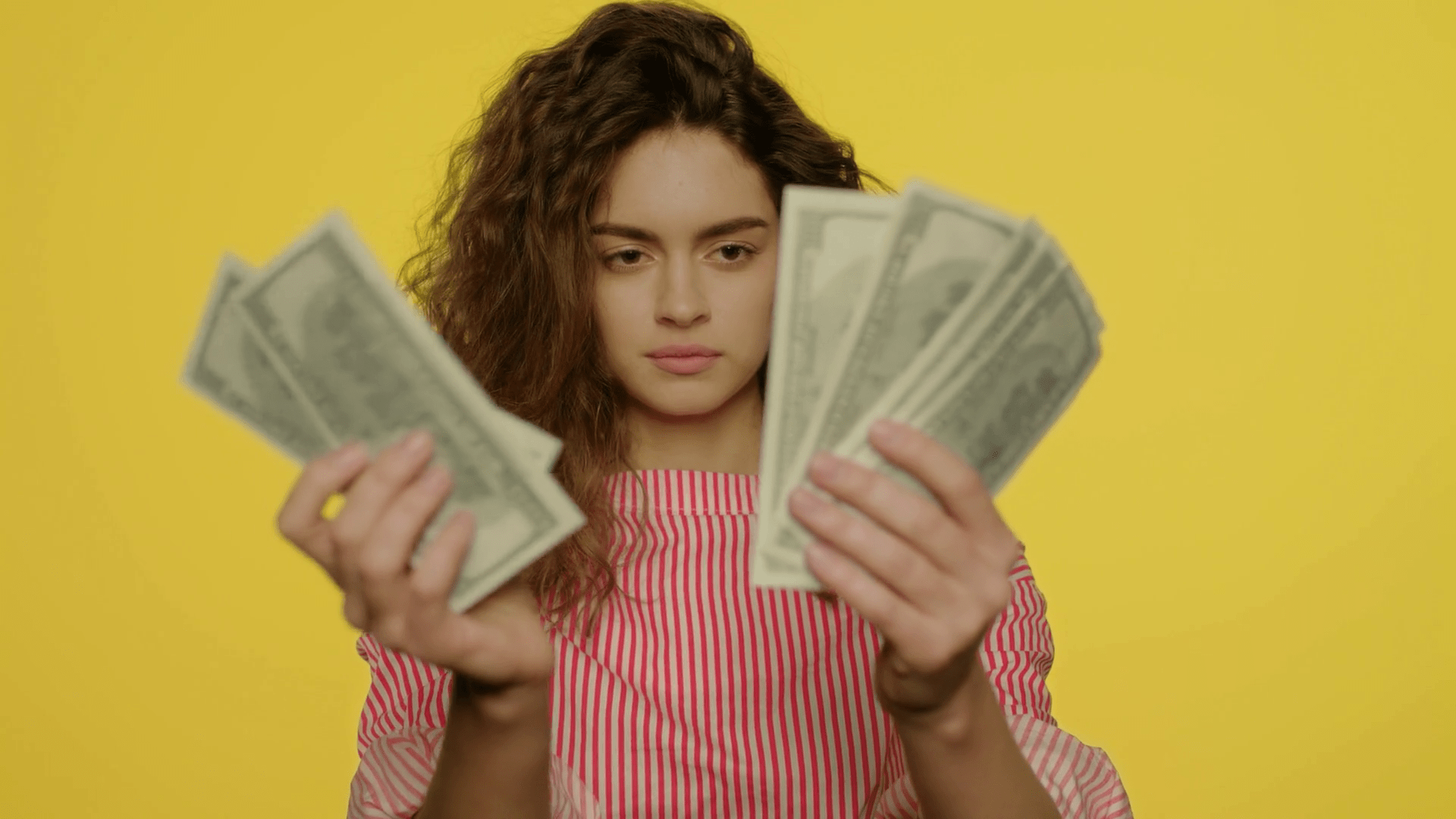 1920x1080 Portrait of a young woman counting money in slow motion. Female student counting dollar bills on yellow background