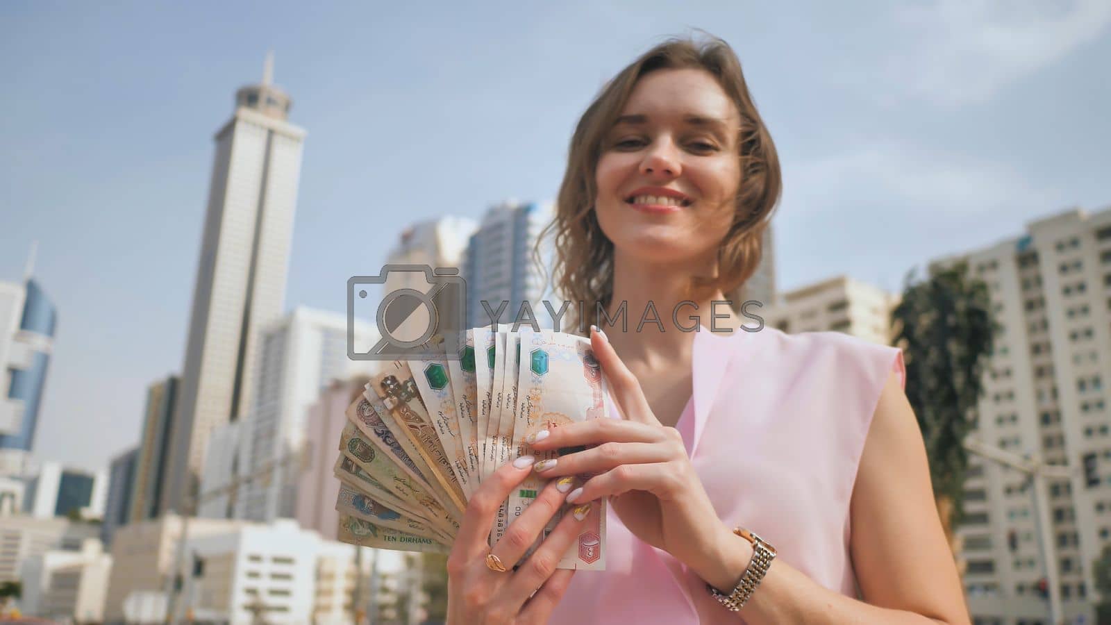 1600x900 The girl holds in her hands the money of the United Arab Emirates on the background of the city center of Dubai. by DovidPro Vectors & Illustrations with Unlimited Downloads