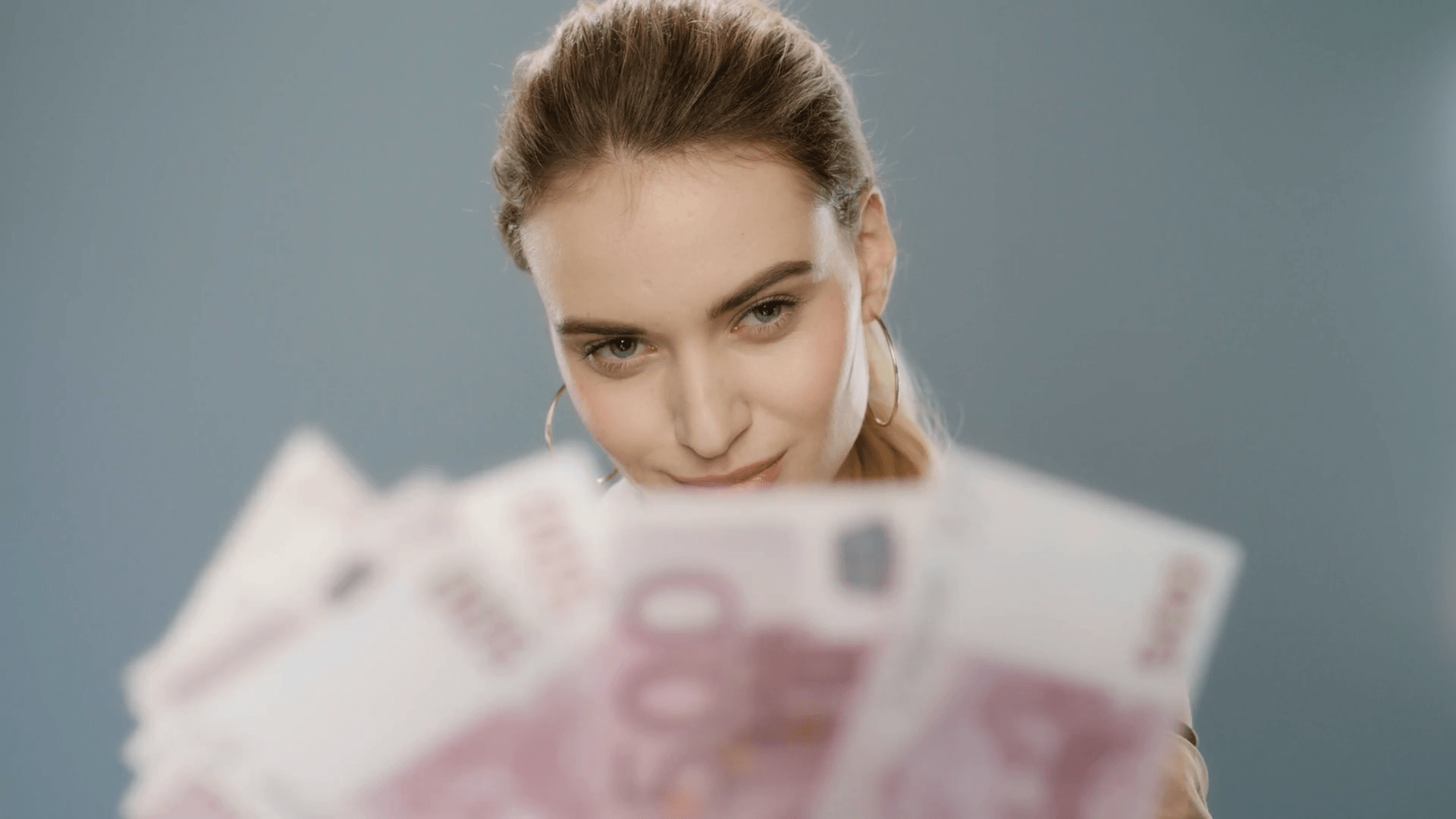 1920x1080 Rich business woman counting money cash in slow motion. Successful woman counting euro banknotes on gray background in studio. Portrait of businesswoman counting cash money profit. Rich girl concept