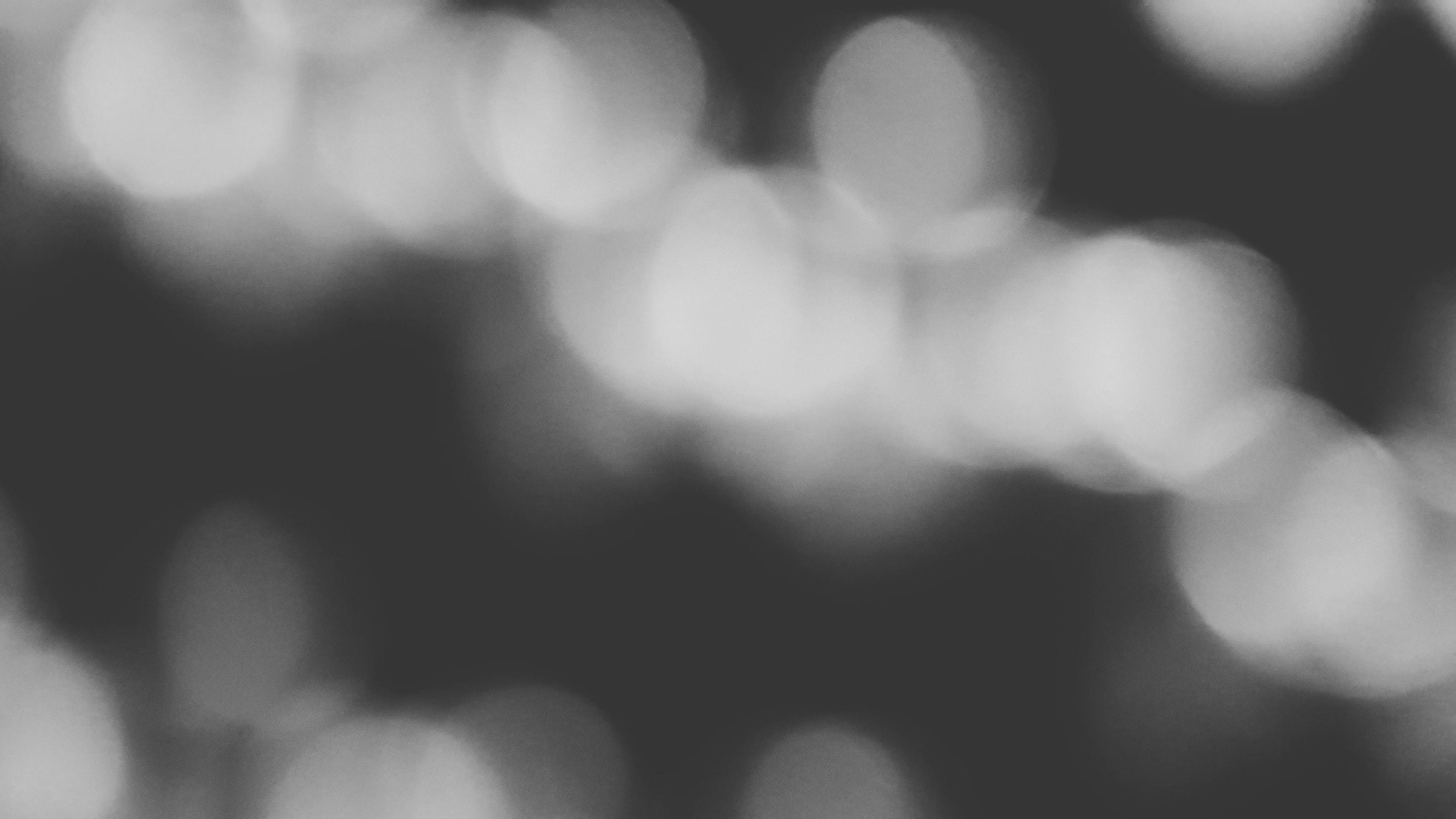 3484x1960 Blurred white Bokeh of light on black background in monochrome or black and white tone. Green lighting blurry wallpaper