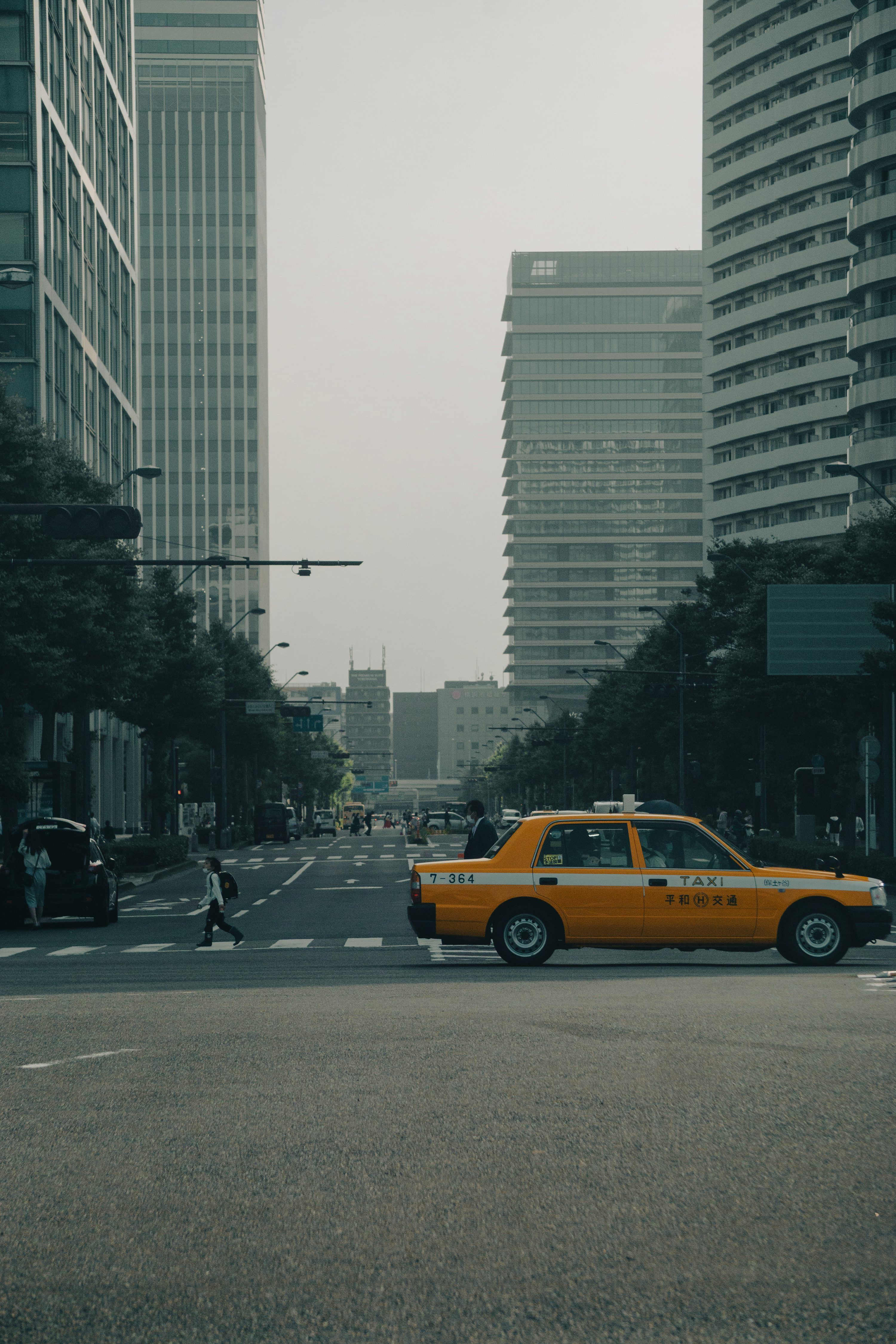 3000x4500 A yellow taxi cab driving down a street next to tall buildings photo